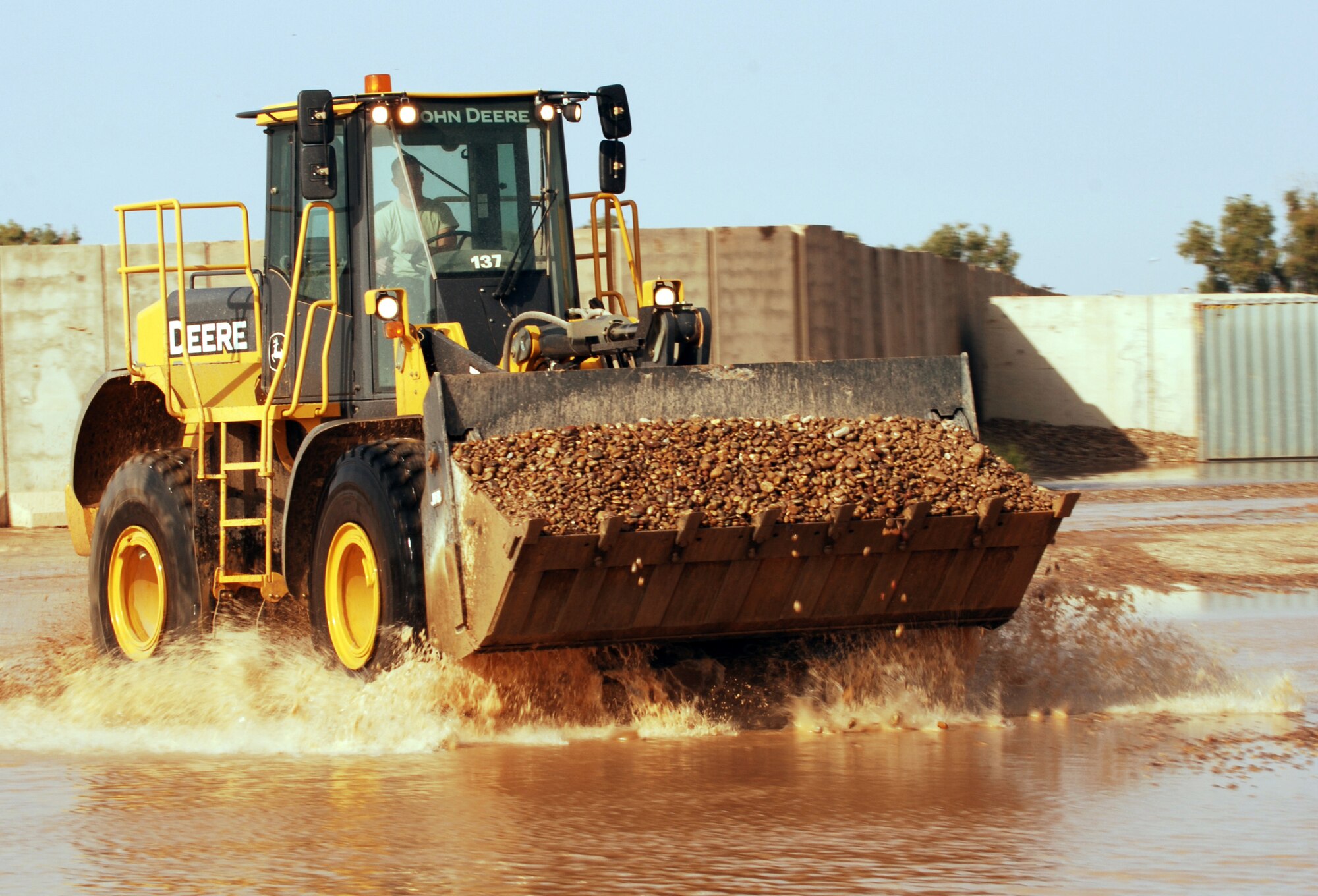 A front end loader plows through a flooded area of Joint Base Balad, Iraq, with a load of rock to build up low areas Oct. 25. Because rain is infrequent in Iraq, when it does rain, the hardened ground soaks up little water. (U.S. Air Force photo/Tech. Sgt. Erik Gudmundson)