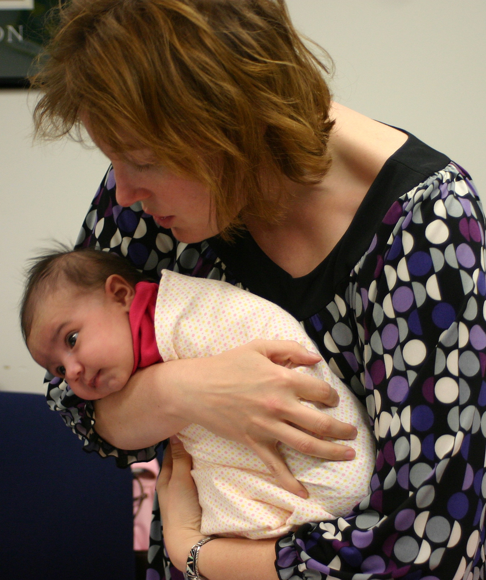 Amy Thomas, Family Advocacy nurse, demonstrates principles of the Happiest Baby on the Block program by first swaddling 1-month-old Trinity Castle, then shifting her to her side, bouncing her and "shooshing" until she calms and eventually begins drifting off to sleep. The Happiest Baby class is provided free of charge by Family Advocacy and is designed to give parents of newborns the tools they need to calm their baby and help him or her sleep longer. (U.S. Air Force photo/Senior Airman Danielle Johnson)