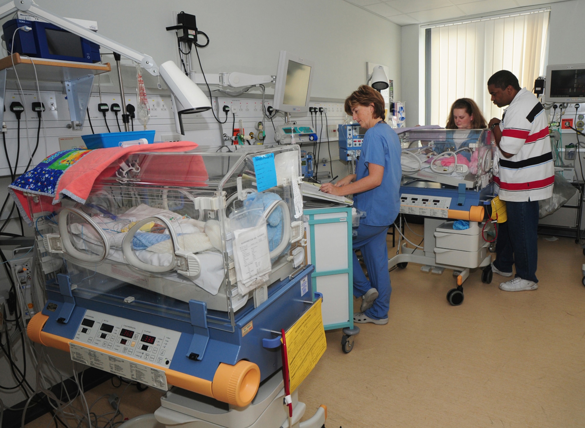 Staff Nurse Jane Foster, Norfolk and Norwich University Hospital NeoNatal Unit, fills out the observation chart for Alexis Frazier, one of premature twins born Sept. 6, as the babies' parents, Mandy and Tech. Sgt. Barry Frazier, 100th Air Refueling Wing Legal Office, watch Alexis in her incubator. Her twin brother, Eric, in the left incubator, weighed 1 pound, 5 ounces at birth, and his sister weghed 1 pound, 3 ounces. As of Oct. 21, age 6 weeks and 2 days, both babies weighed about 1 pound, 13 ounces, but this includes excess fluid they both have at present. (U.S. Air Force photo by Karen Abeyasekere)