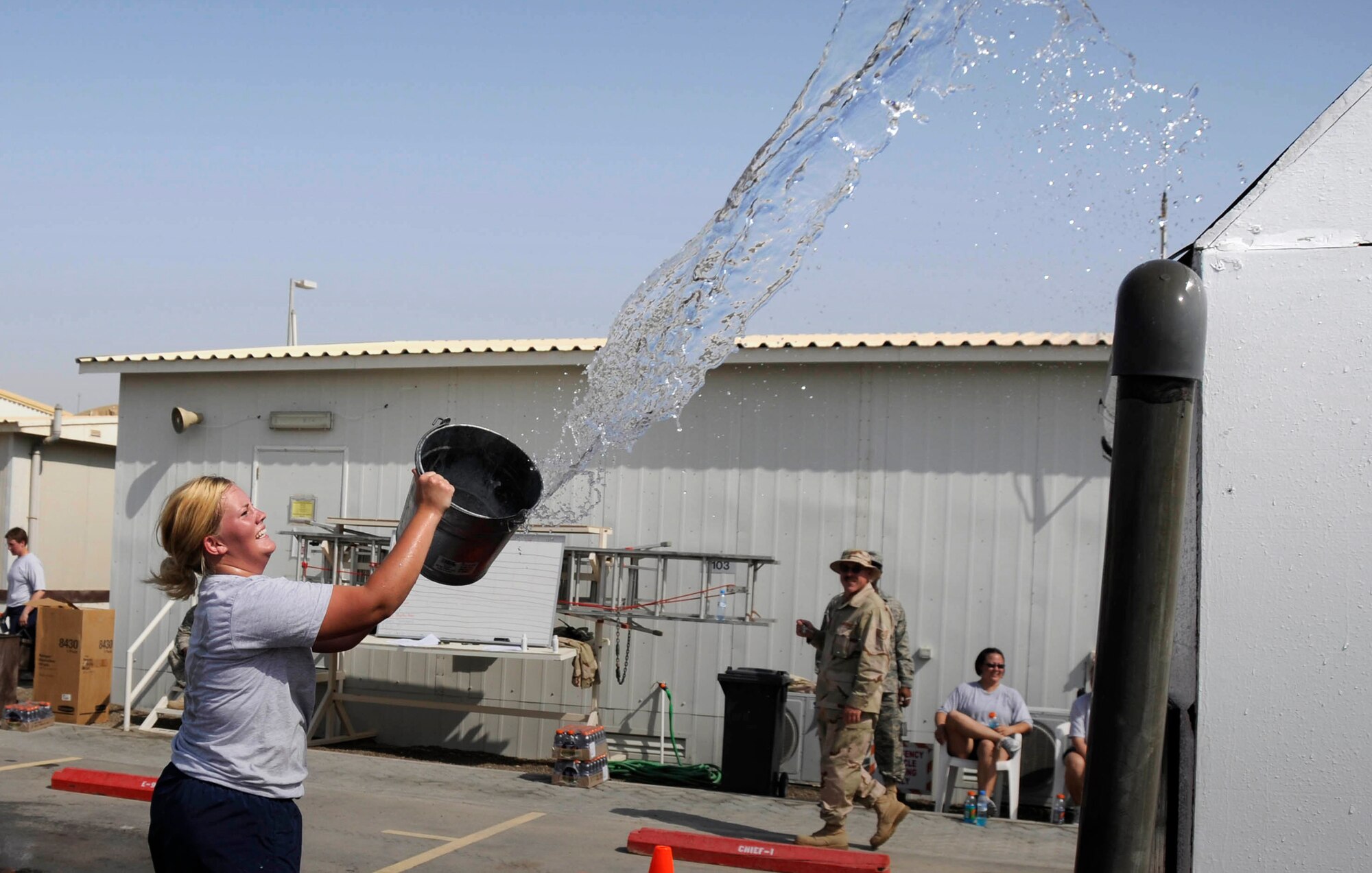 SOUTHWEST ASIA -- Senior Airman Mandy Herrmann works against time to fill a trash can with water during a fire muster here. Airman Herrmann's team the "Happy Houligans" were at the bucket brigade event where the team has to fill a can with water and dousing a house fire in the process.  The Expeditionary fire department held a fire muster for morale and team building.  (U.S. Air Force photo/Tech. Sgt. Christopher A. Campbell)(released)