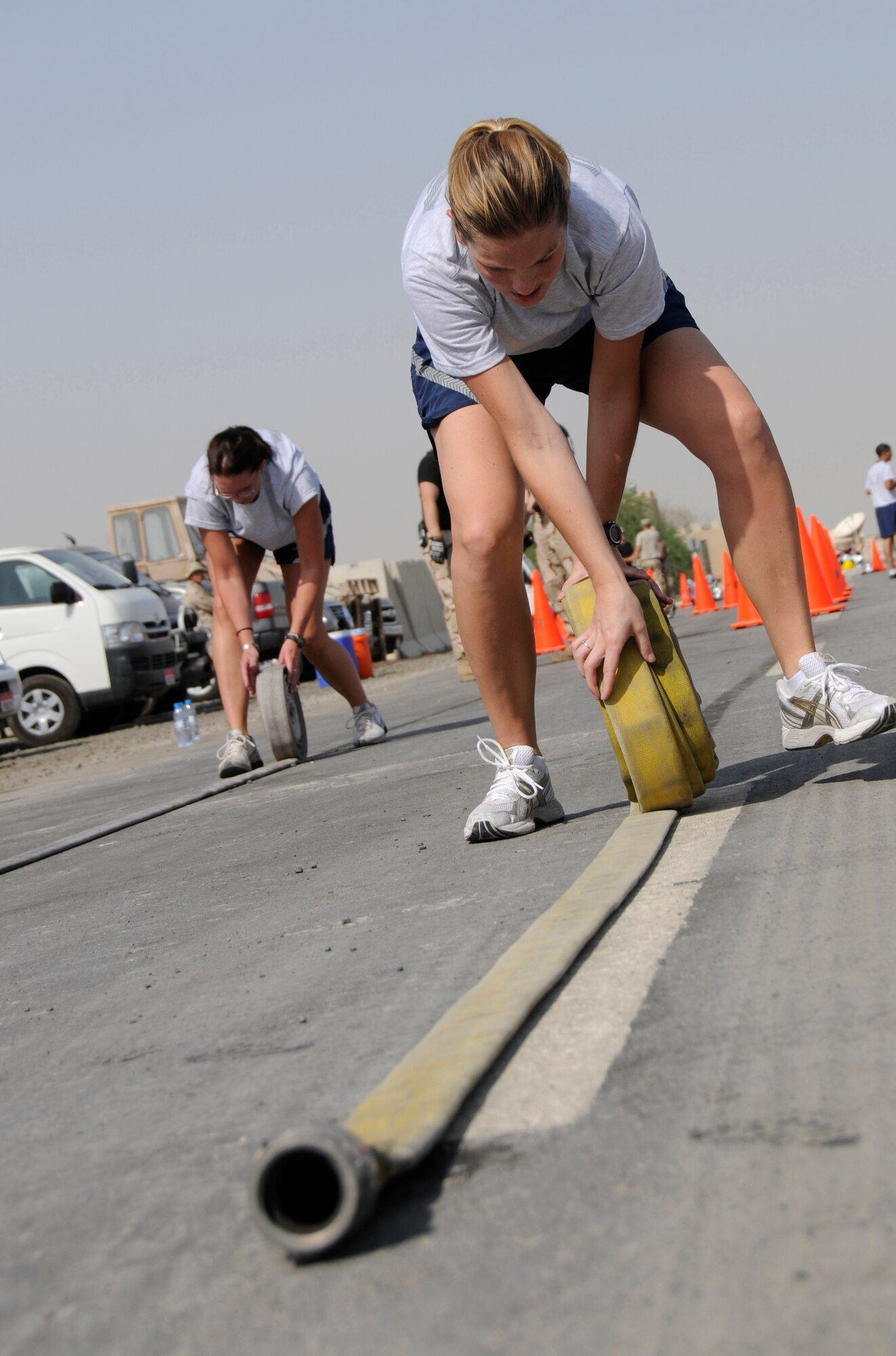 SOUTHWEST ASIA -- Tech. Sgt. Jodi Renschler rolls up a fire hose during a fire muster here. Sergeant Renschler's team, the "Happy Houligans," were at the bucket brigade event where the team had to fill a can with water by dousing a house fire in the process. The Expeditionary fire department held a fire muster for morale and team building.  (U.S. Air Force photo/Tech. Sgt. Christopher A. Campbell)(released)