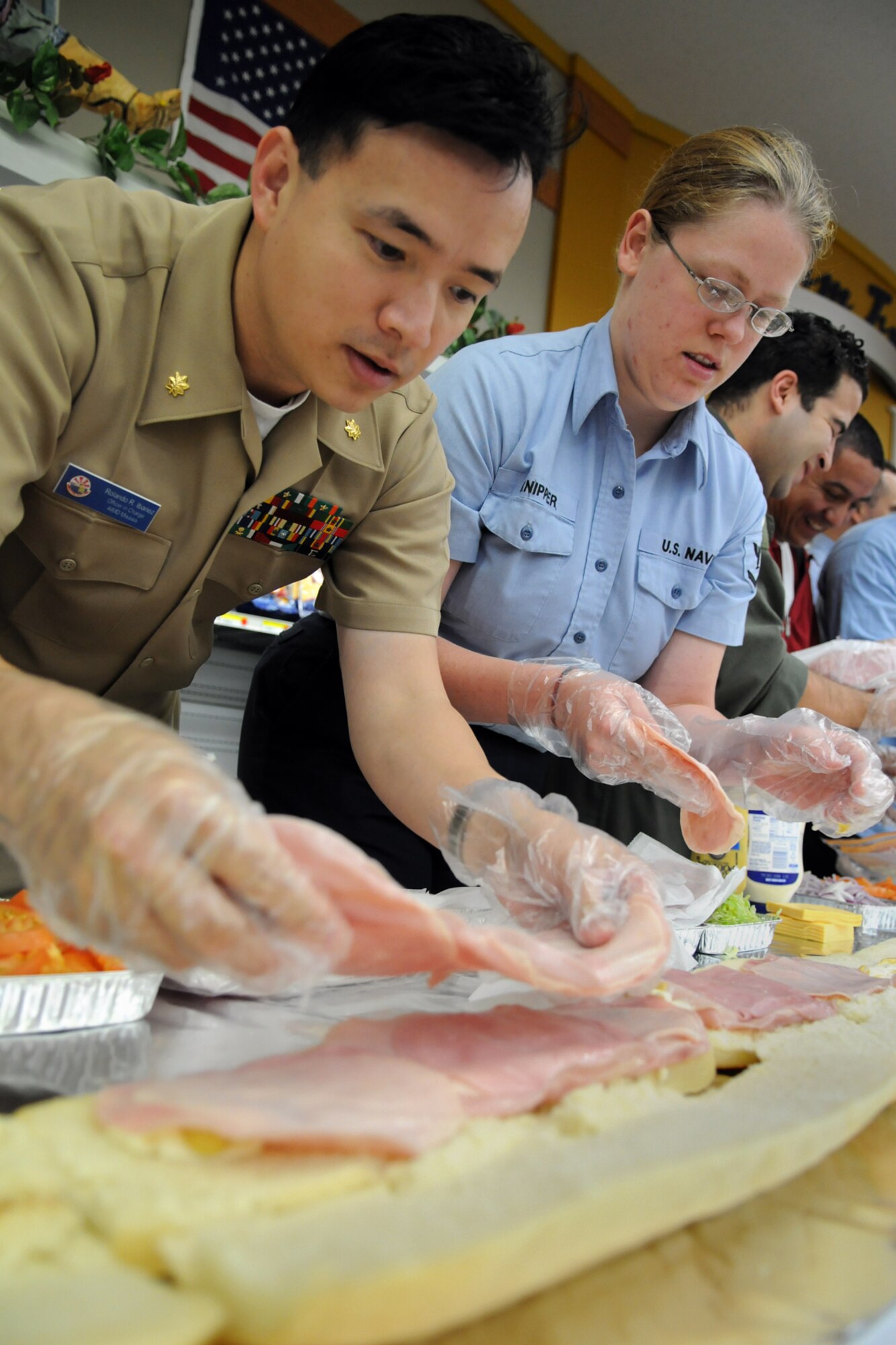 MISAWA AIR BASE, Japan -- Lt. Cmdr. Roland Ibanez, Aircraft Intermediate Maintenance Detachement Misawa officer in charge, and Petty Officer 3rd Class Angela Knipper, Aircraft Intermediate Maintenance Detachment Misawa, add ham to Misawa's Longest Submarine Sandwich at the commissary Oct. 24, 2008. The two, along with more than 30 of their Navy comrades, spread mayonnaise, laid ham and cheese and added lettuce and tomato in an effort to make Japan's longest submarine sandwich in history. (U.S. Air Force photo by Airman 1st Class Jamal D. Sutter)