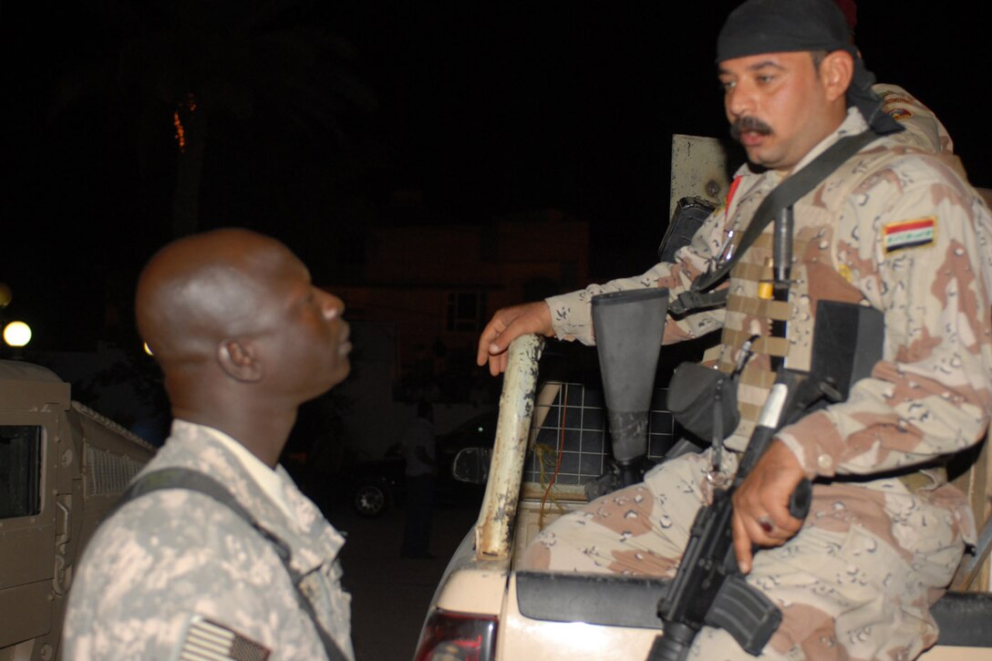 U.S. Army Spc. Wilson Alnar, an Arabic translator with the Multinational Division Center Public Affairs Office and a native of Sudan, speaks with an Iraqi soldier while on a mission in Kut, Iraq, Oct. 3, 2008. U.S. Army photo by Maj. Tommy Spagel