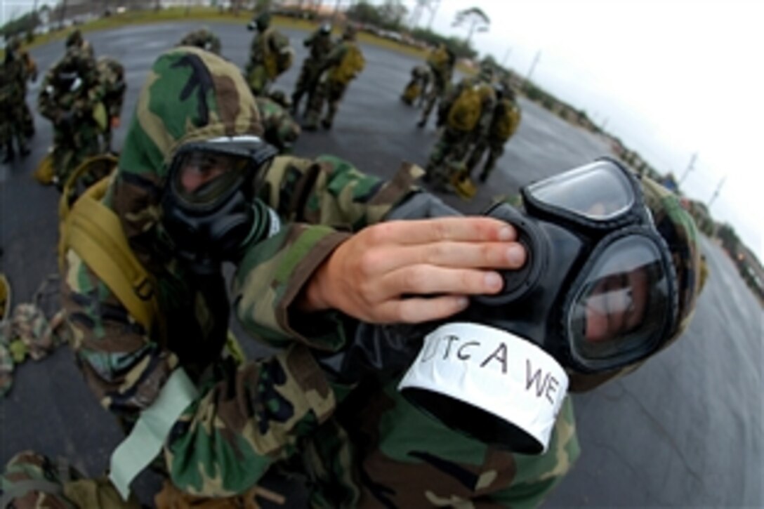 U.S. Navy Seaman Robert Weiss holds his MCU-2P gas mask in place while a fellow Seabee tightens his overhood during a chemical, biological and radiological warfare drill on Naval Construction Battalion Center, Gulfport, Miss., Oct. 24, 2008. Weiss is a utilitiesman constructionman apprentice assigned to Naval Mobile Construction Battalion 1.