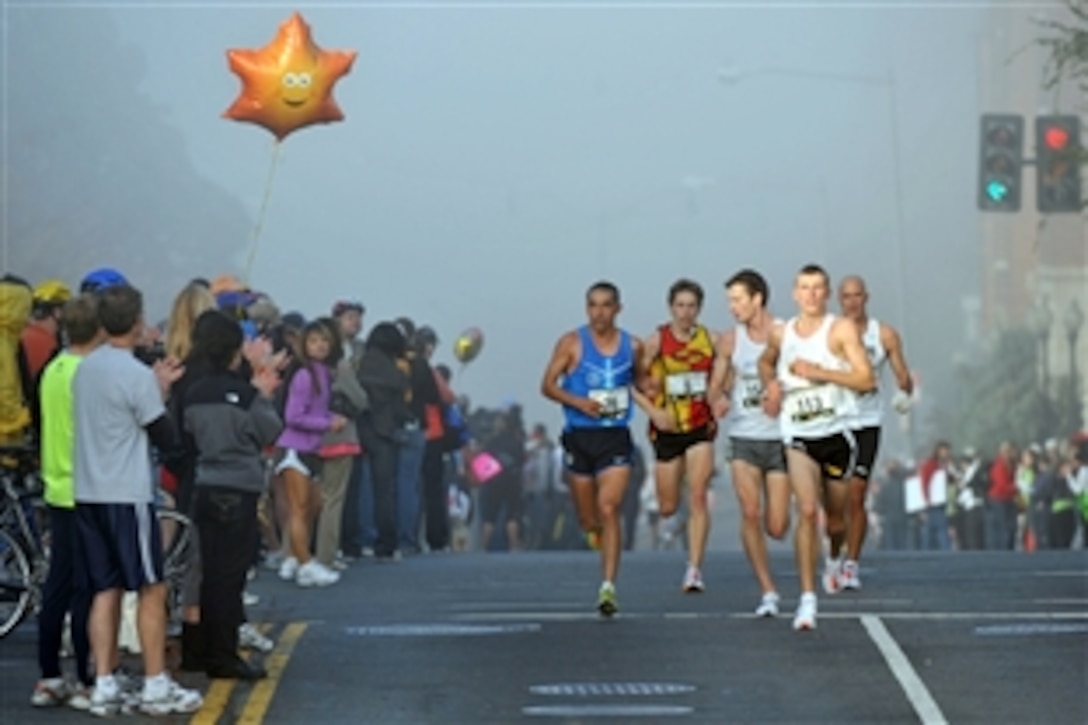 The sun shines through early morning mist on U.S. Army 2nd Lt. Kenneth Foster, wearing bib number 113, as he paces the lead pack down M Street in Georgetown, Washington, D.C., during the 33rd Marine Corps Marathon on Oct. 26, 2008. Eventual race winner Andrew Dumm (156) of Washington runs on Foster's shoulder and is flanked by second-place finisher Fred Joslyn (5) of Rochester, Mich., and sixth-place finisher Jose Miranda (76) of Mexico.
