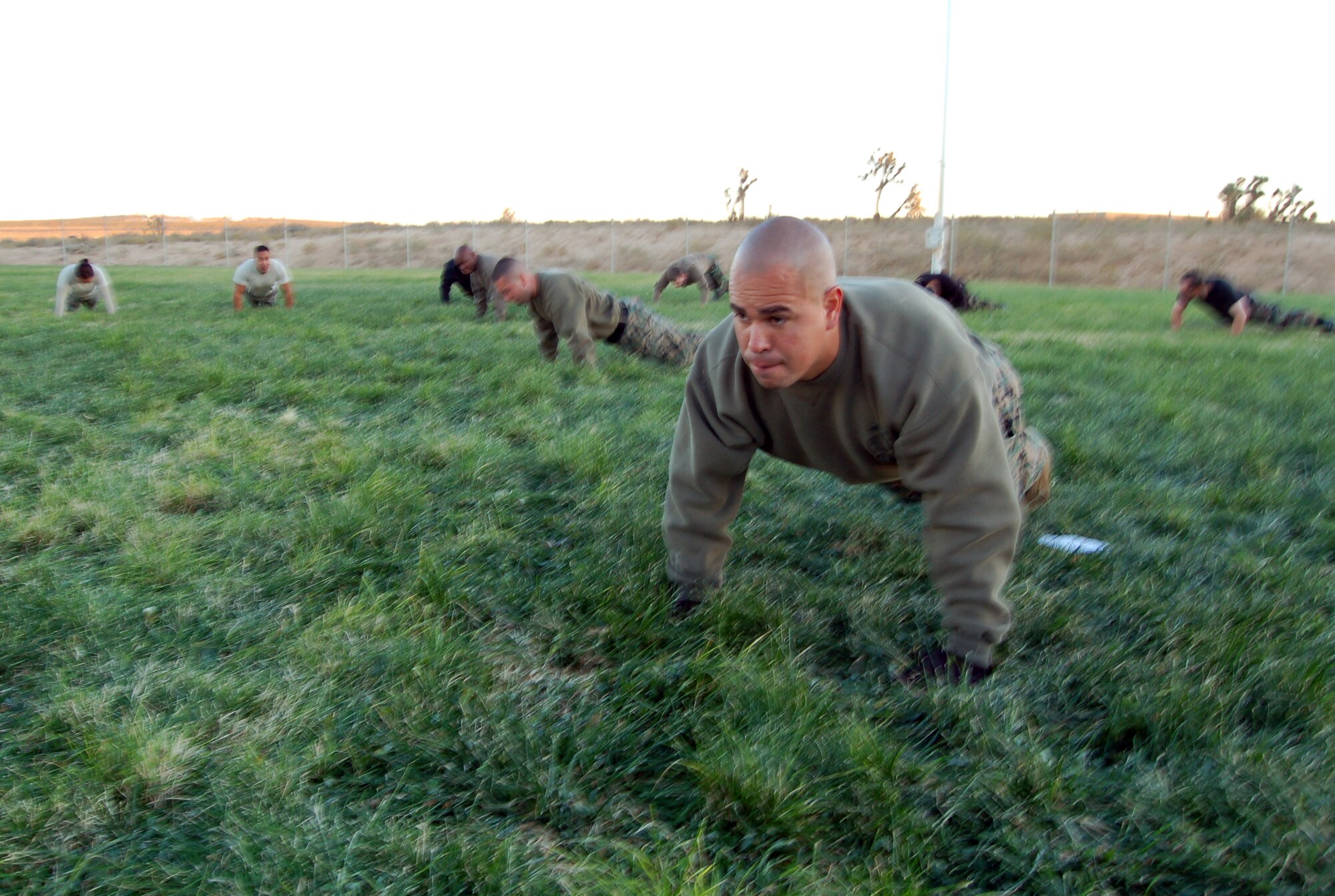 Marine Staff Sgt. Frank Timke, Marine Medium Helicopter Squadron 764 aviation supply specialist, leads Edwards medics in performing a pushup as part of stretching and warm up exercises for a Marine Corp Martial Arts Program introductory course. (Air Force photo by Senior Airman Julius Delos Reyes)