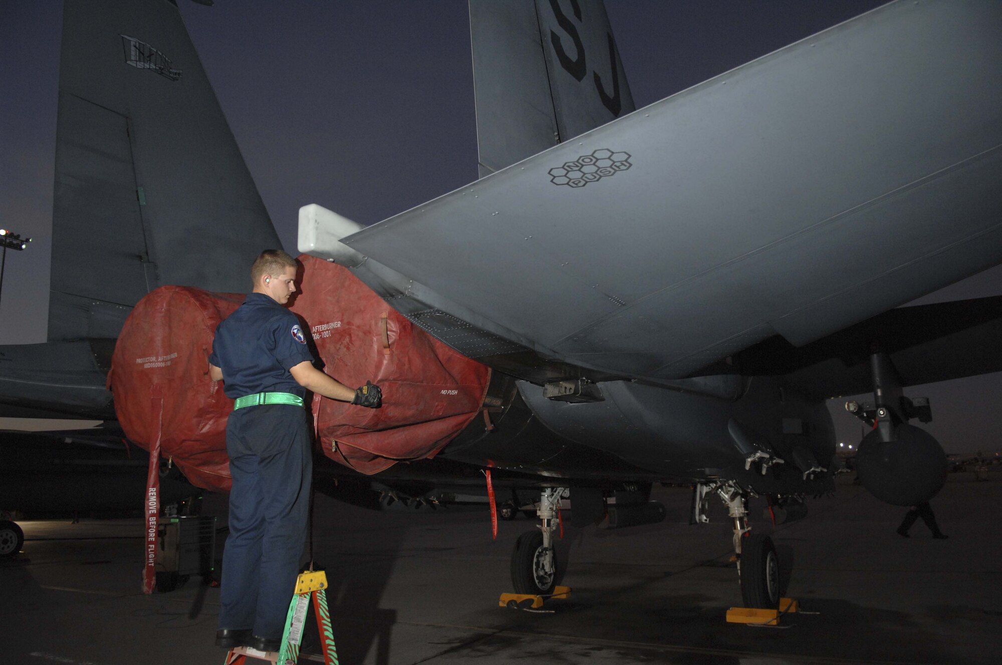 Senior Airman Ken Badertscher, an F-15E crew chief assigned to the 4th Aircraft Maintenance Squadron, Seymour Johnson Air Force Base, N.C., places exhaust covers on his aircraft during Red Flag 09-1at Nellis AFB, Nev., Oct. 24. Red Flag is a multi-national exercise providing a realistic environment to practice combat scenarios. The experience gained during the exercise is vital to the survival of pilots in combat. (U.S. Air Force Photo by Senior Airman Larry E. Reid Jr.)