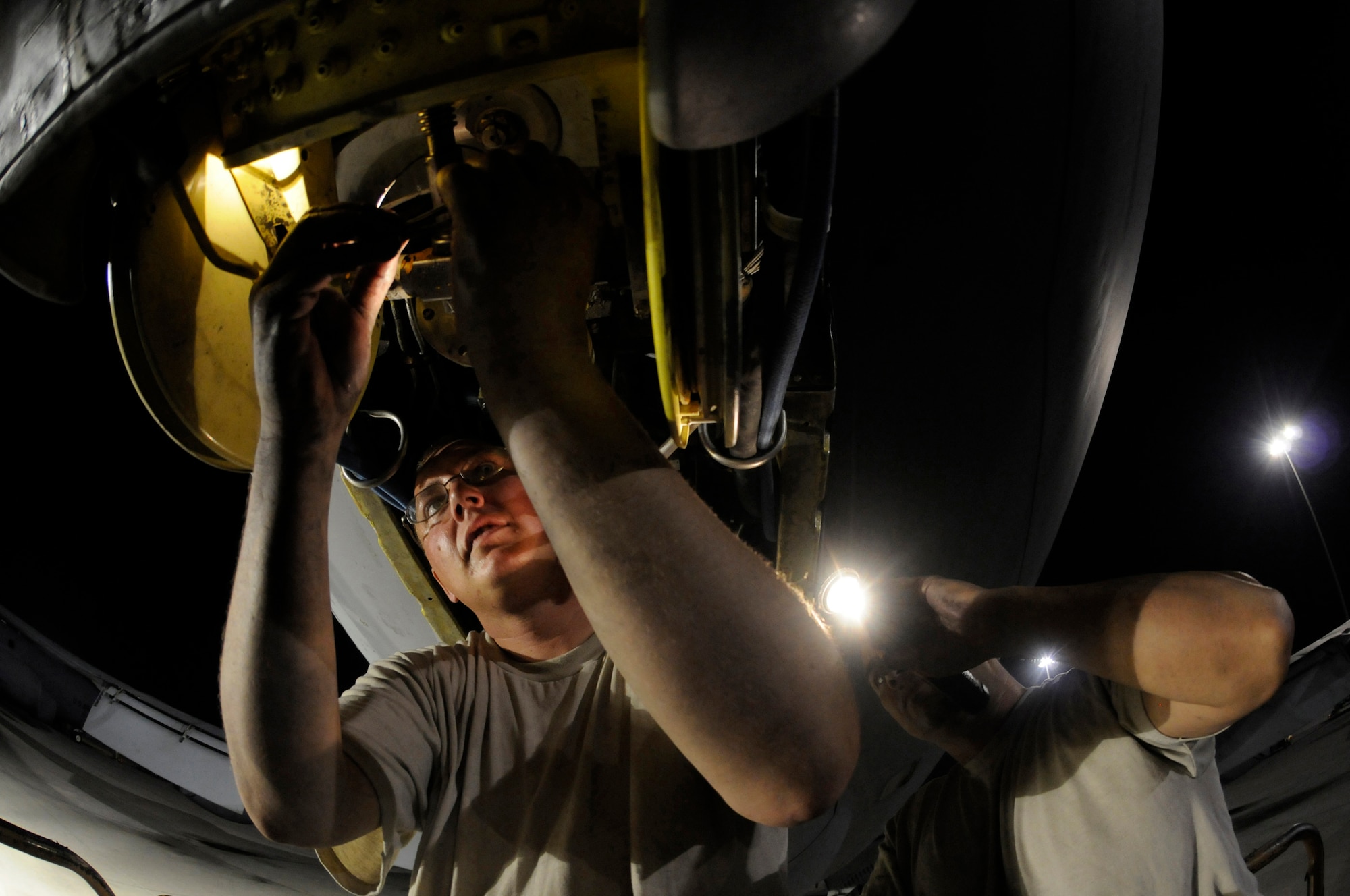 Tech. Sgt. Matthew Massey holds a flashlight while Staff Sgt. Joshua Gill reseals a slide gland of a KC-135 Stratotanker boom October 27, at an undisclosed air base in Southwest Asia.  The KC-135 provides the core aerial refueling capability for the United States Air Force and also provides aerial refueling support to Navy, Marine Corps and allied nation aircraft operating in the Central Command area of responsibility.  Sergeant Massey, a native of Wichita, Kan., and Sergeant Gill, a native of Fonda, N.Y., are both hydraulic technicians assigned to the 379th Expeditionary Aircraft Maintenance Squadron, deployed from McConnell Air Force Base, Kan., in support of Operations Iraqi and Enduring Freedom and Joint Task Force-Horn of Africa.  (U.S. Air Force photo by Staff Sgt. Darnell T. Cannady/Released)