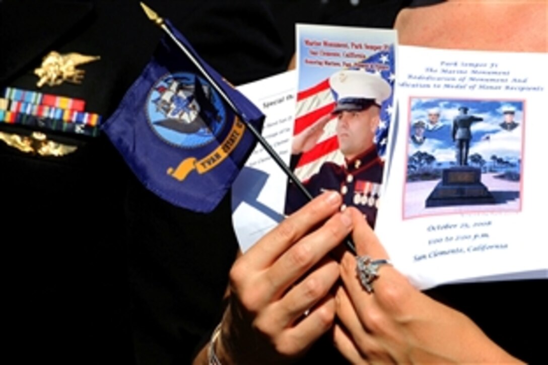 A spectator holds a program and a U.S. Navy flag during the Park Semper Fi Marine Monument re-dedication ceremony in San Clemente, Calif., Oct. 25, 2008. The ceremony honored Medal of Honor recipients Master-at-Arms 2nd Class Michael Monsoor, Cpl. Jason Dunham and Lt. Michael Murphy with memorial plaques.