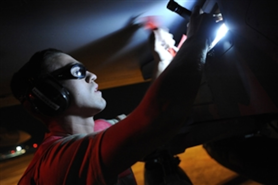 U.S. Air Force Senior Airman Johnny Powell retrieves a safety pin from the wing weapons pylon of an F-16 Fighting Falcon aircraft on a hot cargo pad at Joint Base Balad, Iraq, on Oct. 21, 2008.  Safety pins prevent unintentional deployment of munitions once the aircraft has landed.  Powell is assigned as a weapons load crew member to the 332nd Expeditionary Aircraft Maintenance Squadron.  