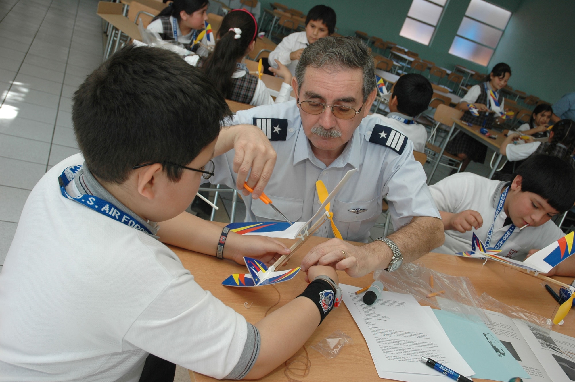 A Chilean air force officer assists a group of students at the Complejo Educacional Esperanza School in Santiago, Chile, during a community outreach event on Oct. 27. The model airplane kits were donated by a Silicon Valley technology company for use with Operation Southern Partner, an Air Forces Southern-led exchange aimed at providing intensive, periodic subject matter exchanges with partner nations in the U.S. Southern Command area of focus.  Included in the exchange is visits like this one where Airmen partnered with local U.S. Embassy volunteers, Chilean air force officers, members of the U.S. Military Group and volunteers from Agilent Technologies to teach children about the practical applications of the sciences.  (U.S. Embassy photo/Jose Nuños)