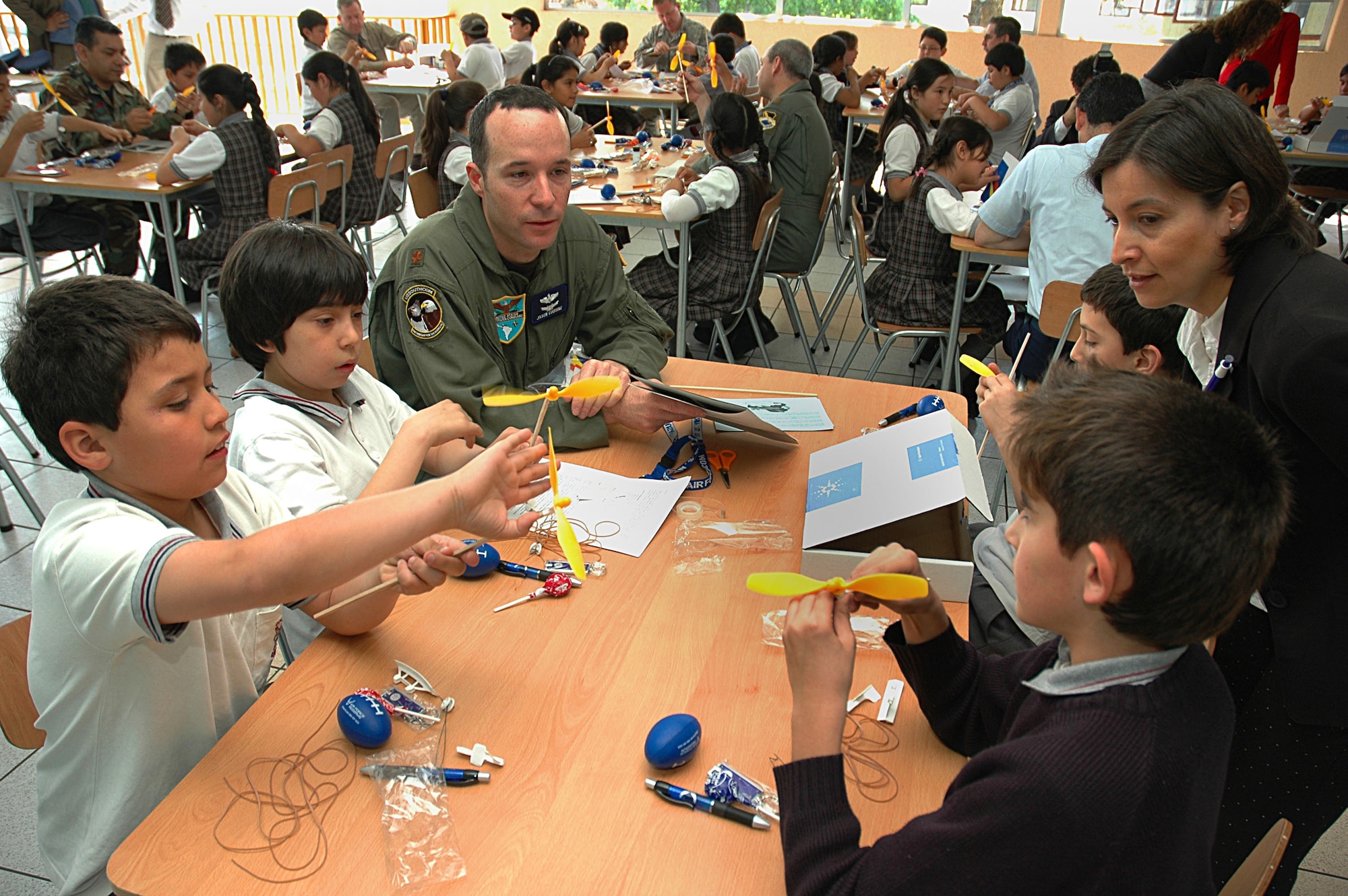 Maj. Jason Couisine, the Air Force section chief at the U.S. Military Group in Chile, assists a group of students at the Complejo Educacional Esperanza School in Santiago, Chile, during a community outreach event on Oct. 27. The model airplane kits were donated by a Silicon Valley technology company for use with Operation Southern Partner, an Air Forces Southern-led exchange aimed at providing intensive, periodic subject matter exchanges with partner nations in the U.S. Southern Command area of focus.  Included in the exchange is visits like this one where Airmen partnered with local U.S. Embassy volunteers, Chilean air force officers, members of the U.S. Military Group and volunteers from Agilent Technologies to teach children about the practical applications of the sciences.  (U.S. Embassy photo/Jose Nuños)