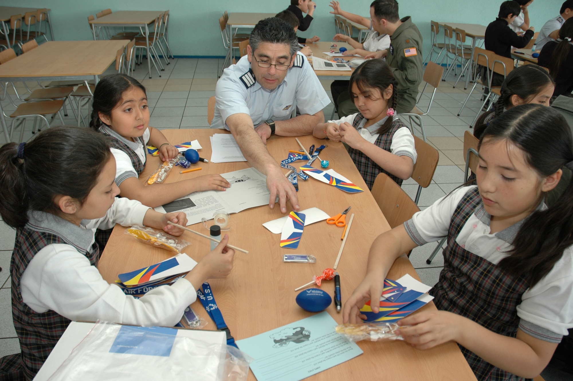 A Chilean air force officer assists a group of students at the Complejo Educacional Esperanza School in Santiago, Chile, during a community outreach event on Oct. 27. The model airplane kits were donated by a Silicon Valley technology company for use with Operation Southern Partner, an Air Forces Southern-led exchange aimed at providing intensive, periodic subject matter exchanges with partner nations in the U.S. Southern Command area of focus.  Included in the exchange is visits like this one where Airmen partnered with local U.S. Embassy volunteers, Chilean air force officers, members of the U.S. Military Group and volunteers from Agilent Technologies to teach children about the practical applications of the sciences.  (U.S. Embassy photo/Jose Nuños)