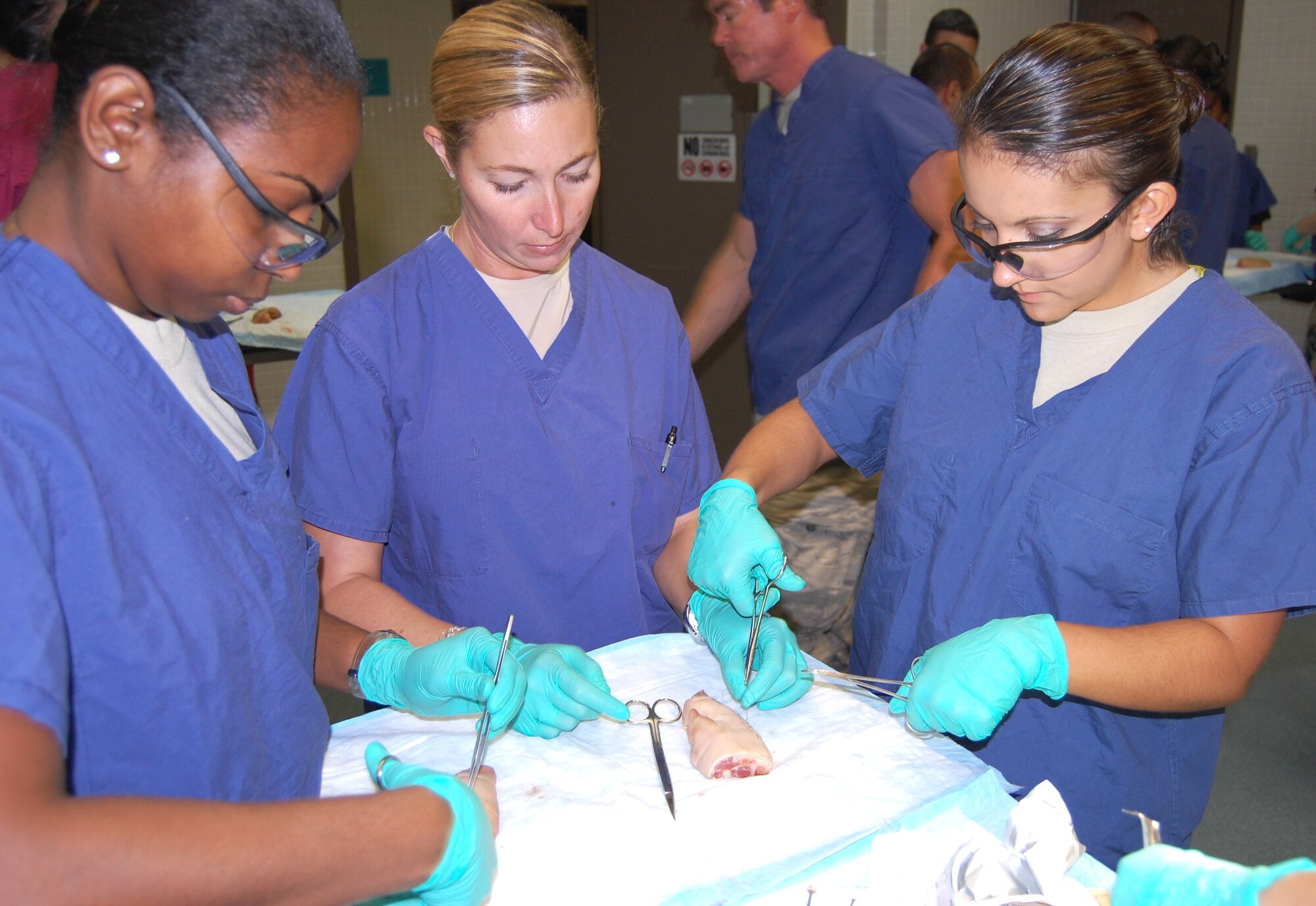 Photo by Steve Pivnick
Using a pig’s foot, residents Capt. (Dr. ) Portia Willis, left, and Capt. (Dr.) Nicole Vazquez, right, demonstrate different suture techniques to Maj. (Dr.) Karyn Young, assistant director of the 81st Dental Squadron Advanced Education in General Dentistry residency program.  Oral maxillofacial surgeons from the 81st DS recently provided dental residents and staff members the opportunity to sharpen their suturing techniques during a hands-on course held at the 81st Medical Support Squadron Clinical Research Laboratory.  “This course will enhance dentists' readiness capabilities in deployed situations and in garrison, “ Col. (Dr.) William Dunn, military consultant to the surgeon general for medical ethics and 81st DS director of education, explained.
