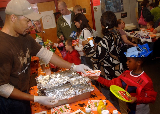 Arthur Chatman serves a hotdog to Makhi Jenkins during the fall festival on base Oct. 24. The base Youth Programs sponsored the fall festival with games, prizes and a costume contest for military families. Arthur is a chef for Youth Programs and Makhi is the son of Senior Airman Clarence Jenkins who is with the 437th Security Forces Squadron. (U.S. Air Force photo/Airman 1st Class Timothy Taylor)
