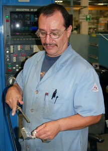 Louis Macias, a machinist with the 530th Commodities Maintenance Squadron at Hill Air Force Base, Utah, air blasts a newly manufactured T-38 aileron lever to remove excess coolant following the third machine operation. (U.S. Air Force photo/Bill Orndorff) 
