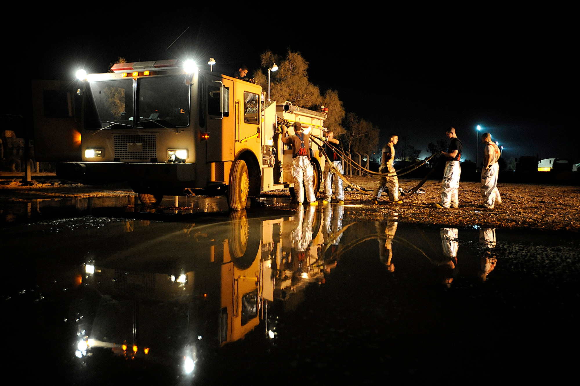 Firefighters load hoses onto a fire engine Oct. 22 at Joint Base Balad, Iraq. The Joint Base Balad Fire Department conducted a controlled burn as part of a live-fire training scenario, giving firefighters experience using hose patterns for interior fires. The fire department is comprised of Airmen and Soldiers. (U.S. Air Force photo/Airman 1st Class Jason Epley) 
