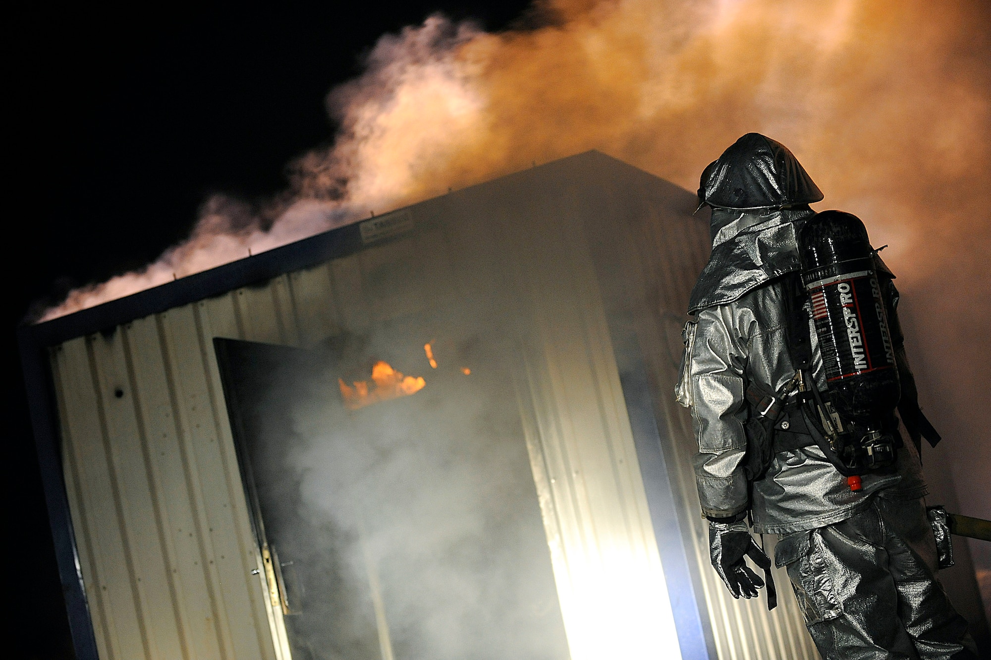 Senior Airman Timothy Weller monitors a burning structure during a controlled burn Oct. 22 at Joint Base Balad, Iraq. Airman Weller is a member of the Joint Base Balad Fire Department, which conducted the burn as part of a live-fire training scenario to give individual firefighters experience using hose patterns on interior fires. He is deployed to the 332nd Expeditionary Civil Engineer Squadron from MacDill Air Force Base, Fla. (U.S. Air Force photo/Airman 1st Class Jason Epley) 