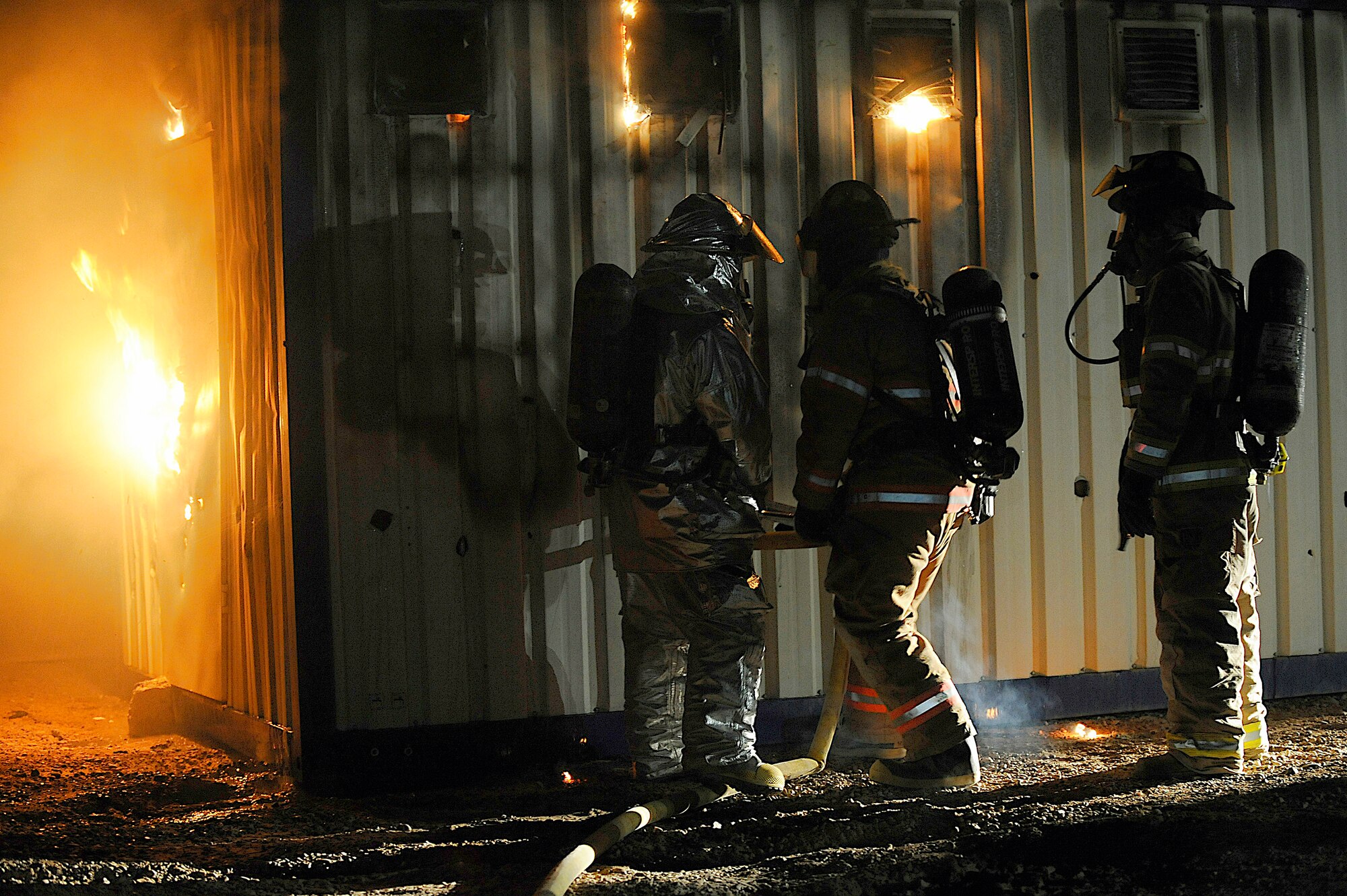 Staff Sgt. Steven Wade, Staff Sgt. Kristopher Doughty, and Army Staff Sgt. Joshua Nordstrom use a piercing nozzle to extinguish flames during a live-fire training exercise Oct. 22 at Joint Base Balad, Iraq. The nozzle allows firefighters to work from outside the structure. All three servicemembers are assigned to the Joint Base Balad Fire Department, which conducted training to give firefighters experience using hose patterns on interior fires. Sergeant Wade is deployed from McConnell Air Force Base, Kan. Sergeant Doughty is deployed from Fairchild AFB, Wash. (U.S. Air Force photo/Airman 1st Class Jason Epley) 