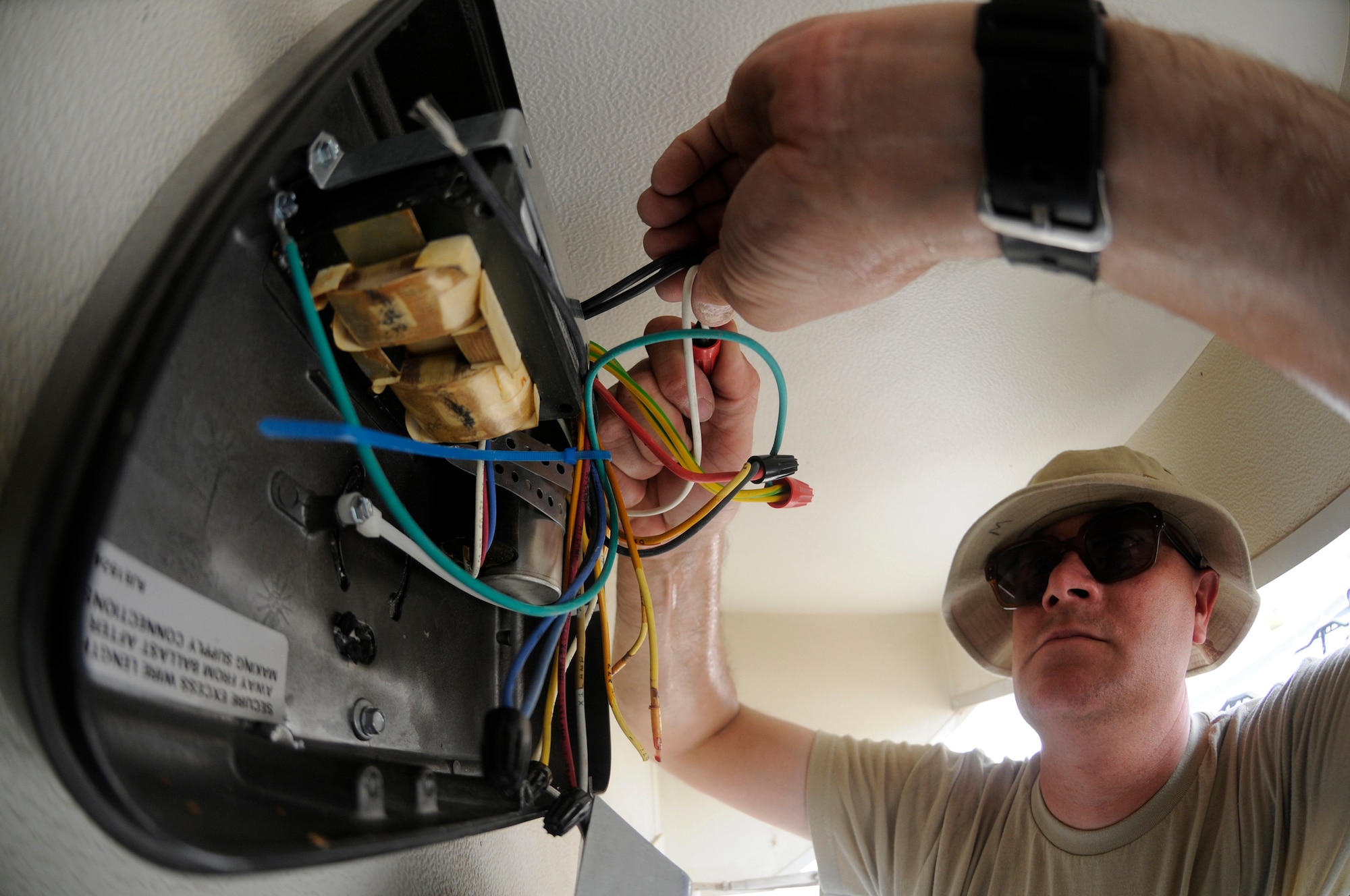 Staff Sgt. Ronald Weech, electrical systems craftsman assigned to the 379th Expeditionary Civil Engineer Squadron, connects wiring on a new light fixture October 28.  The electricians are installing new lighting outside of the post office at an undisclosed air base in Southwest Asia.  Sergeant Weech, a native of Moses Lake, Wash., is deployed from Fairchild Air Force Base, Wash., in support of Operations Iraqi and Enduring Freedom and Joint Task Force-Horn of Africa.  (U.S. Air Force photo by Staff Sgt. Darnell T. Cannady/Released)