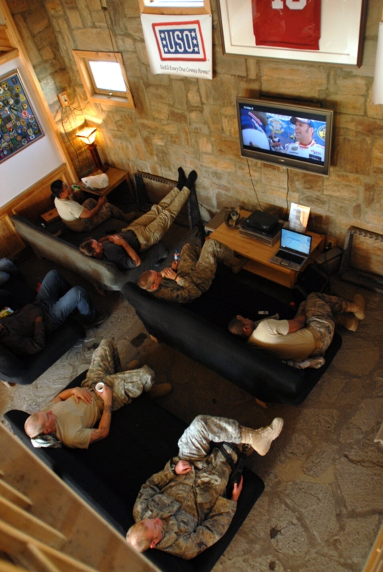Weary U.S. service members and civilians watch a movie while they lounge in the cottage-like United Service Organizations building at Bagram Air Field, Afghanistan. (Photo by Spc. Mary Gonzalez, CJTF-101 Public Affairs)