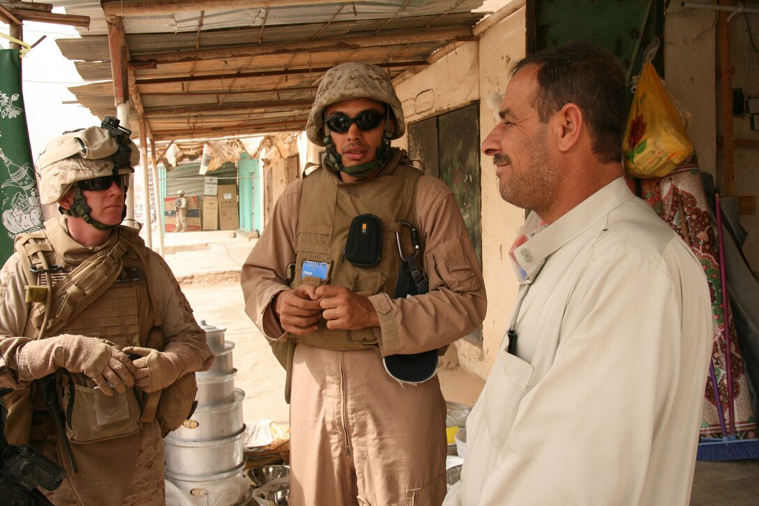 Assisted by an interpreter, Navy Cmdr. (Dr.) Dennis McKenna, left, battalion surgeon and economic line of operations officer with 2nd Battalion, 25th Marine Regiment, Regimental Combat Team 5, speaks with a shop owner in Rutbah, Iraq, Oct. 21, 2008. U.S. Marine Corps photo by Capt. Paul Greenberg