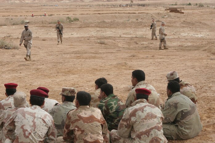 Iraqi Army soldiers watch as Marines with Regimental Combat Team 5 demonstrate patrolling techniques at Al Asad Air Base, Iraq, Oct. 28.  Select Iraqi soldiers were brought to Al Asad to take part in a 12-day advanced infantry training course taught by Marines with RCT-5.  The Marines, and the soldiers themselves, saw a vast improvement in the Iraqi soldiers at the end of the training.::r::::n::