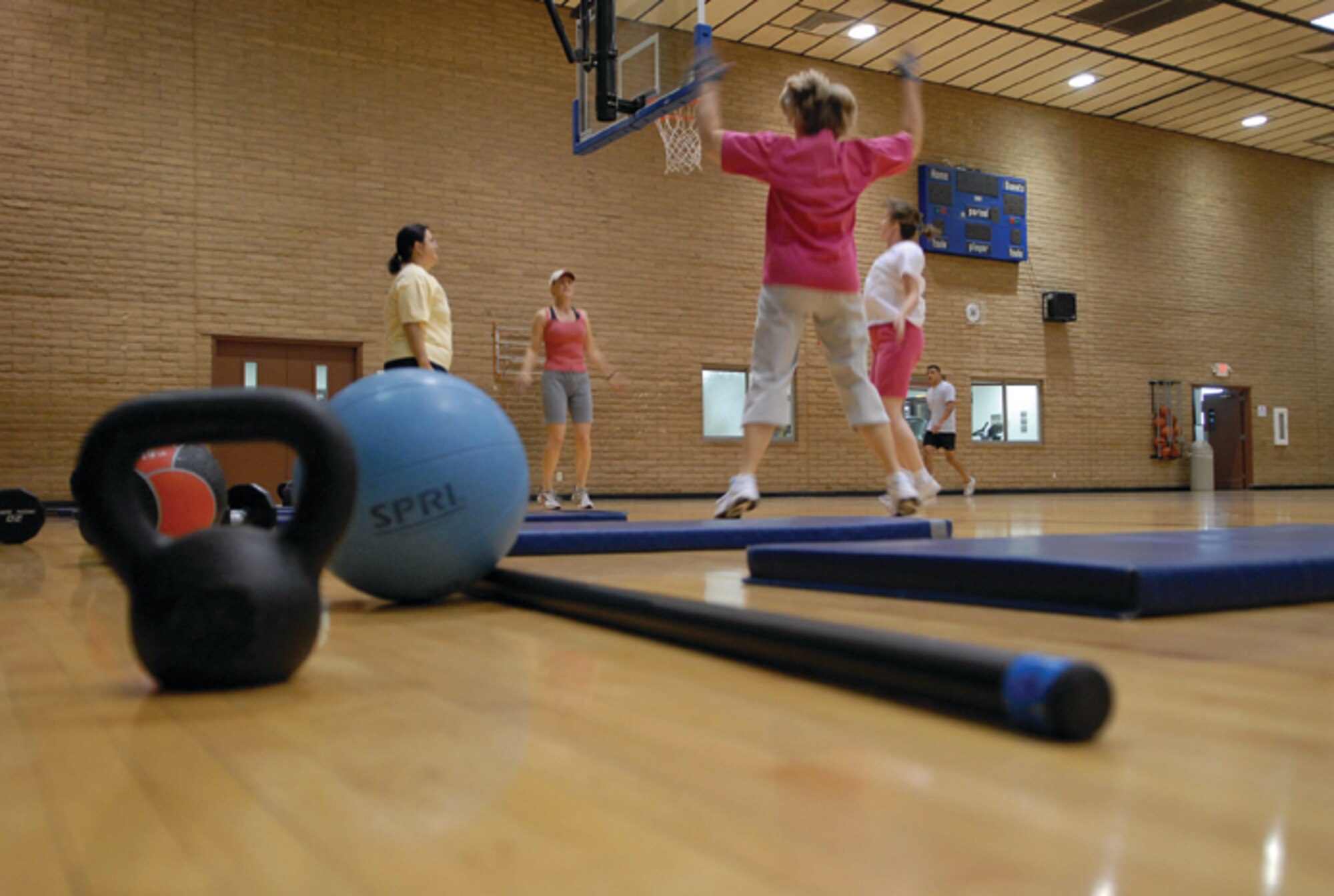 Candy Robinson, Becky Messelheiser and Carol Ann Stentz join Sandy Neubauer, CrossFit level-one certified trainer, for their morning workout of 33 repetitions of the day's six exercises. A mat, weight bar, kettle ball and a medicine ball are all that's needed for today's CrossFit workout. Depending on a person's physical ability the amount of weight lifted can change to meet the individual's needs. (U.S. Air Force photo/ Airman 1st Class C.J. Hatch.)
