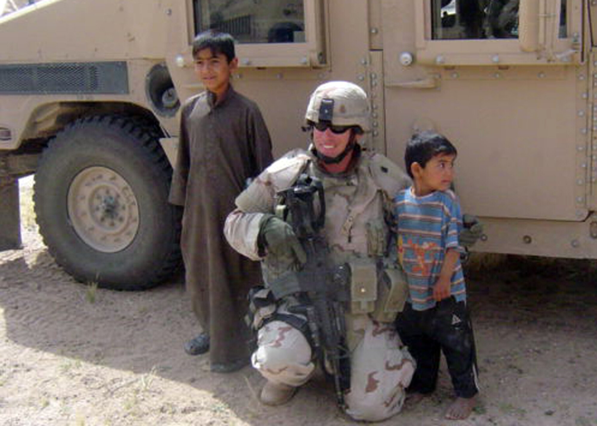SOUTHWEST ASIA -- Under a very watchful eye from his team, Tech. Sgt. Trevor Dunn poses with some local children during a deployment to Southwest Asia. Sergeant Dunn recently won the Air Force Space Command Security Forces Individual Award for Outstanding Security Forces Support Staff Non-Commissioned Officer. (Courtesy photo)          