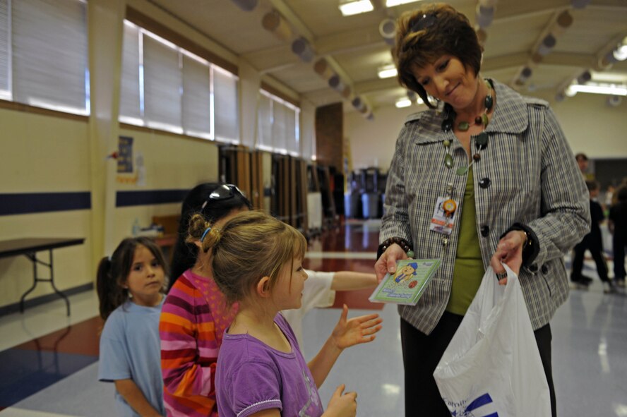 Michelle Henrich, principal of Badger Clark Elementary, hands out Sammy Rabbit cd's to students at Badger Clark Elementary, S.D., Oct. 30. “From every dollar save a dime,” was one of Sammy Rabbit’s main messages expressed to the students. (U.S. Air Force photo by Airman Corey Hook)