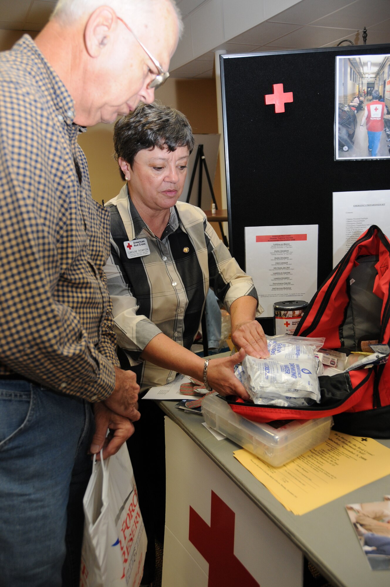 Caroline Thompson, American Red Cross community recovery specialist and retired lieutenant colonel, shows Richard Carter an emergency preparedness kit.  Mr. Carter is a retired master sergeant from Daphne, Ala   (U.S. Air Force photo by Kemberly Groue)