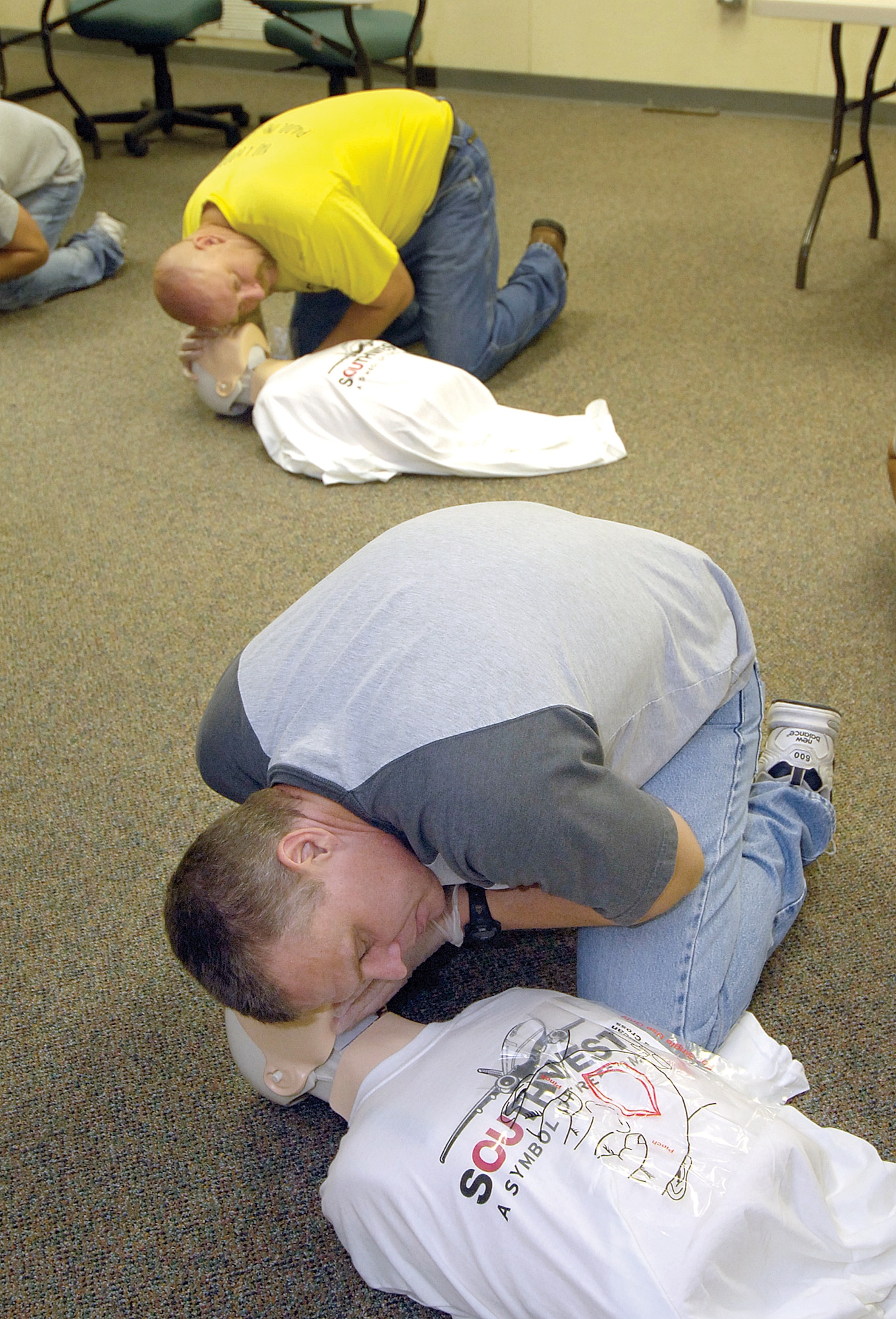 Aaron Adkins, front, and Lorn Van Steenbergh  practice CPR during classes given this summer to 76th Aircraft Maintenance Group personnel by members of Tinker’s 76th Software Maintenance Group who were recognized with a Red Cross award for their efforts. (Air Force photo/Margo Wright)