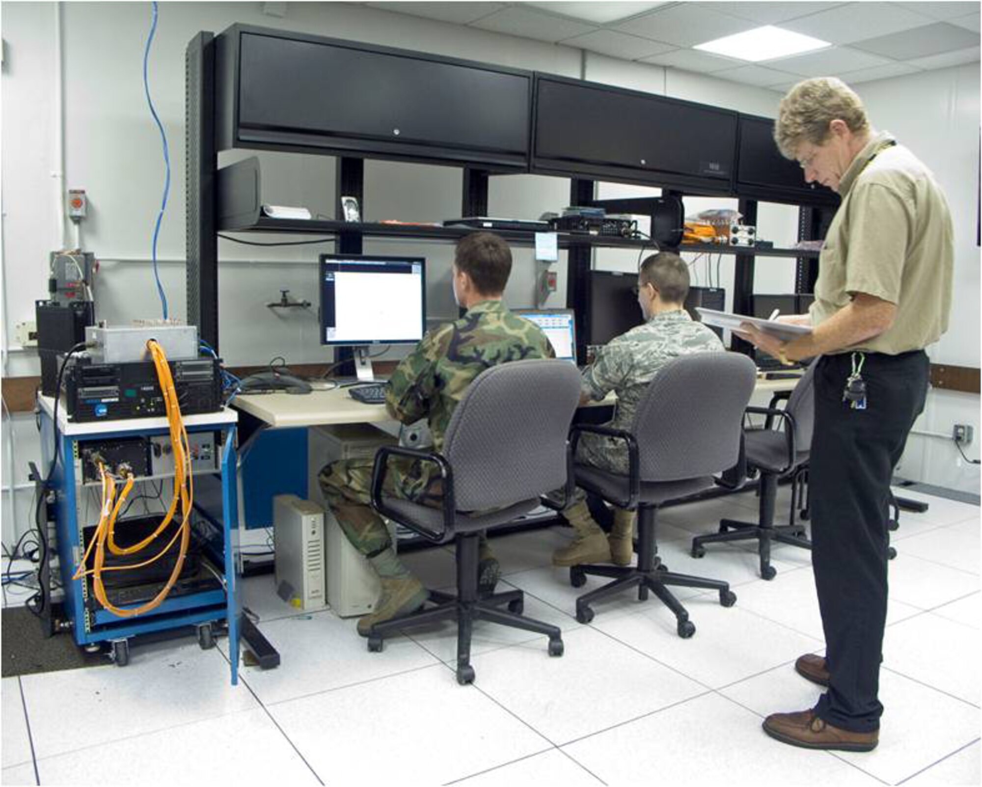2nd Lts. James Baril and Dan Rushton, test engineers, operate the AC-130H lab equipment during lab testing of Link 16 fidelity.  Colin Landen, test engineer for TEAS Corp., takes notes and prepares the team for upcoming Link 16 messages. (courtesy photo)