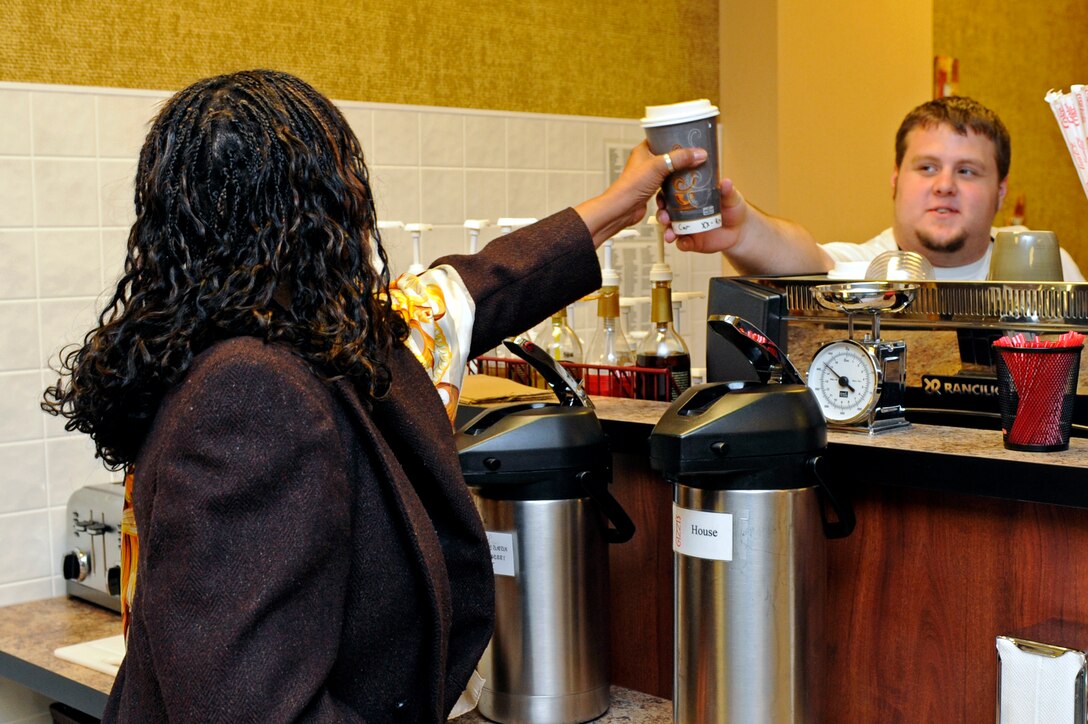 (Right) Andy Shawhan, Gizzi's coffee shop barista, hands Peggy Moore-McCoy, 28th Bomb Wing sexual assault response coordinator, her beverage at Gizzi's coffee shop in Holbrook Library here, Oct. 30. Gizzi's coffee shop celebrated its grand opening Oct. 29 with a ribbon cutting ceremony. Gizzi's hours of operation are Monday through Friday from 6 a.m. to 2:30 p.m. (U.S. Air Force photo/Airman Matthew Flynn)