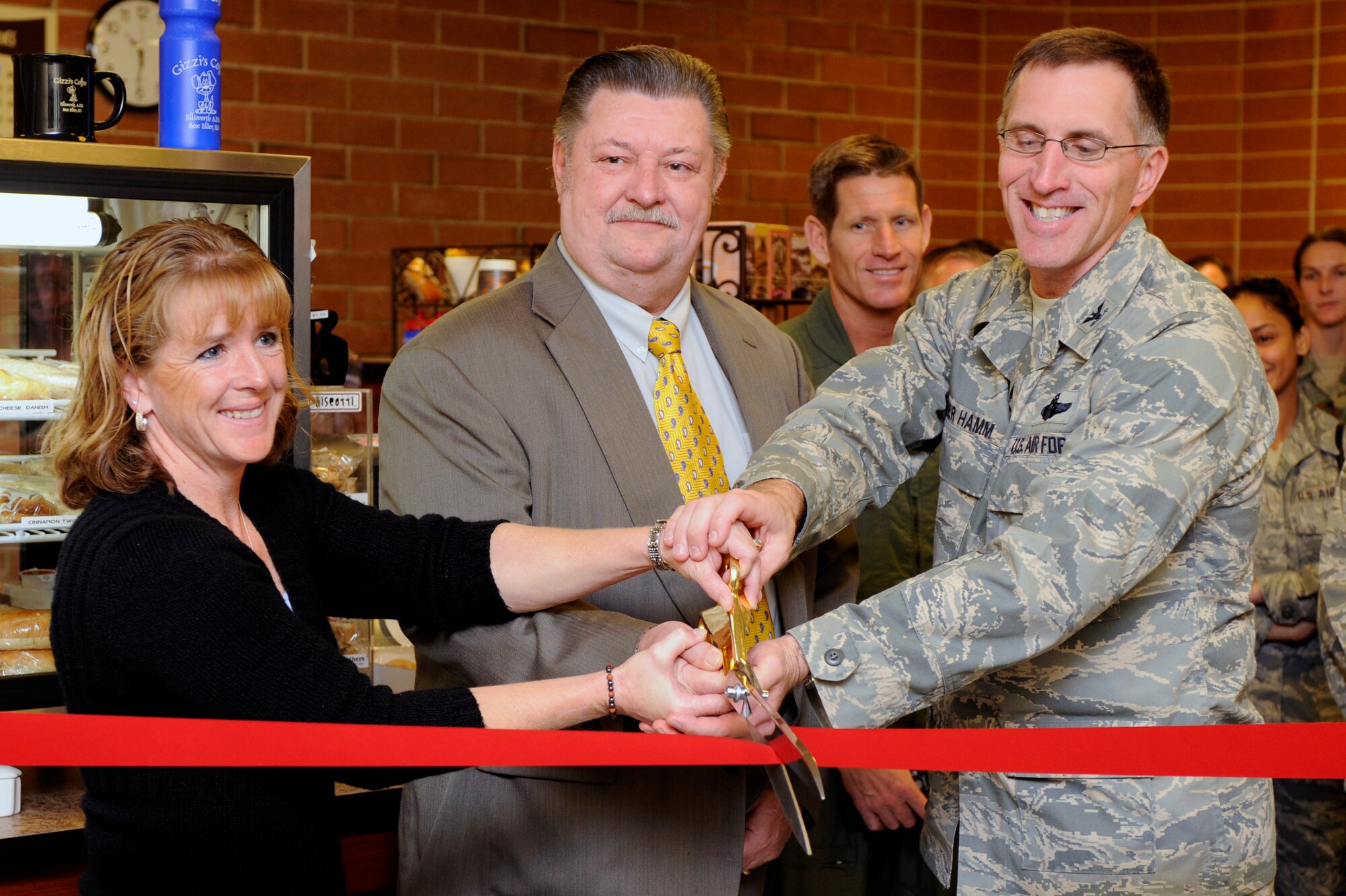 (Left to right) Tracy Scott, Gizzi's coffee shop owner, Don Whalen, 28th Force Support Squadron deputy director, and Col. Scott Vander Hamm, 28th Bomb Wing commander, cut the ribbon during Gizzi's grand opening inside Holbrook Library here, Oct. 29. Gizzi's, a local coffee shop, expanded with a new location here, which provides Airmen a place to read, use wireless internet, and enjoy their favorite beverage. (U.S. Air Force photo/Airman Matthew Flynn)
