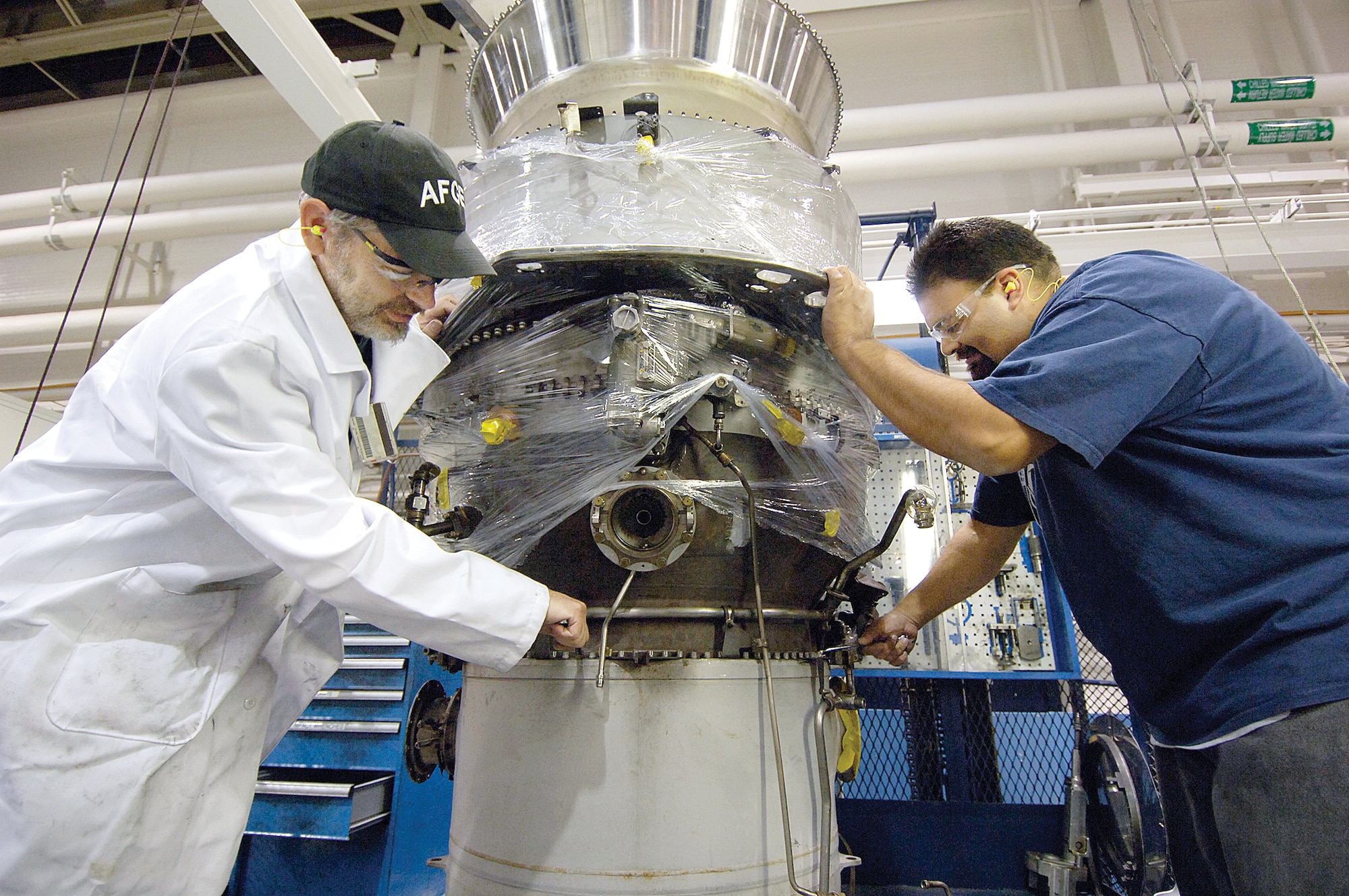 Tinker jet engine mechanics, Raymond Heinken, left, and Eric Puente, install a low speed turbine in a TF33/P100 engine, a powerhouse for the E-3 Sentry. The workload,  now in Bldg. 3001, is scheduled to be one of the first to move into the new Tinker Aerospace Complex.(Air Force photo/Margo Wright)
