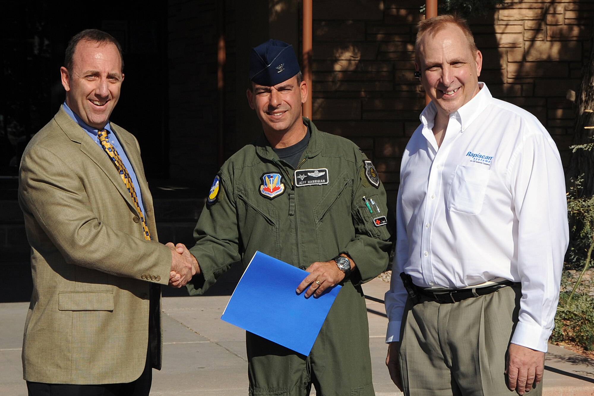 Mr. Ed Mason, IED Defeat Program Office Division Chief, shakes hands with Col. Jeff Harrigian, 49th Fighter Wing commander, along with Mr. John Kuntz, Rapiscan Systems Inc, Manager of Military Sales. Rapiscan Systems donated two Gamma Ray Detection Systems to Holloman Air Force Base, N.M., October 29. Each of the systems is valued at more than one million dollars and are capable of scanning a vehicle for dangerous materials in as little as 30 seconds. (U.S. Air Force photo/Tech. Sgt Chris Flahive)