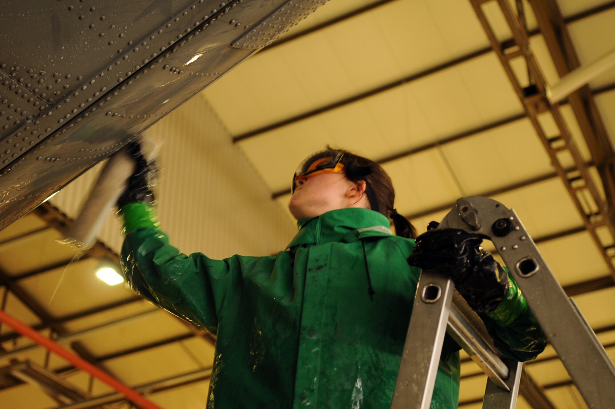 Airman 1st Class Stephanie Hall, 86th Aircraft Maintenance Squadron crew chief, goes up on a ladder to wash the tail end of a C-130E Hercules in Hangar 1, Ramstein Air Base, Germany, Oct. 28, 2008. The wash crew is made up of a 12-member team from the 86th AMXS who wash aircraft every 90 days to keep them mission ready. (U.S. Air Force photo by Airman 1st Class Scott Saldukas)