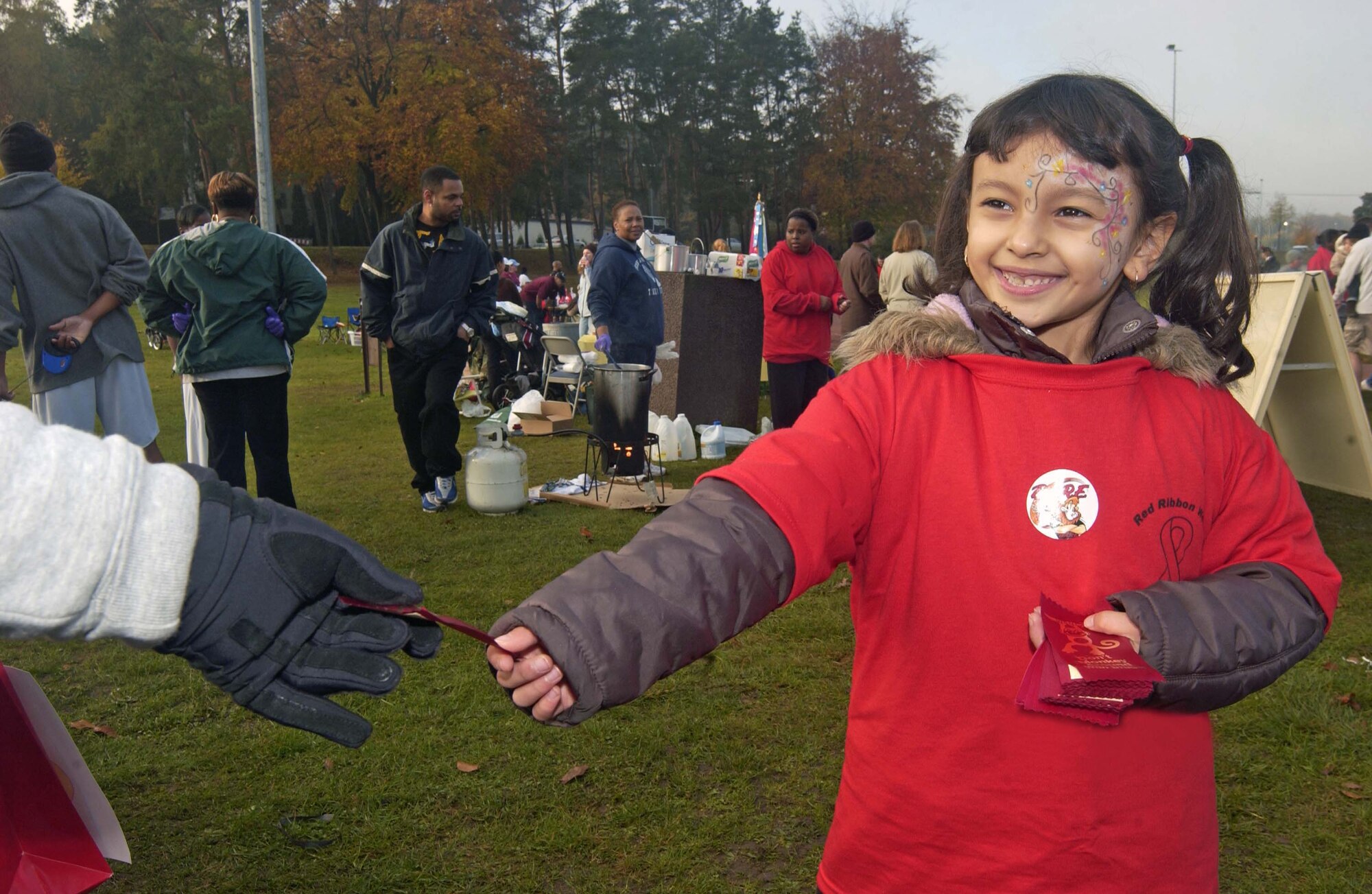 A pledge to live a drug-free life
KAISERSLAUTERN, Germany -- Yvette Mendoza, 6, a Ramstein Elementary School first grader, hands out red ribbons Oct. 25 at the U.S. Army Garrison Kaiserslautern's Red Ribbon Relay held at the track near the Vogelweh Commissary.  More than 630 Soldiers, Airmen, civilians and their family members ran laps - more than double the number of people who participated last year. Close to 70 community members volunteered for the event, which supports Red Ribbon Week. This national observance encourages everyone in the community to take a visible stand against drugs, alcohol and tobacco. One of the traditions of this observance is wearing red badges of satin - red ribbons - as a pledge to lead drug-free lives. U.S. Army photo by Christine June.                              