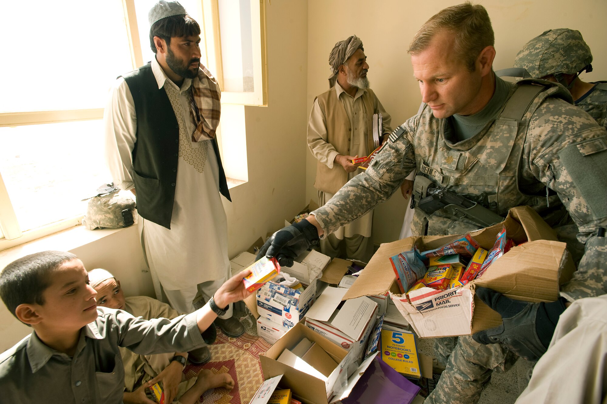 QALAT, Afghanistan – Army Maj. Trever Nehls hands a box of crayons to an Afghan boy. The Zabul Provincial Reconstruction Team delivered enough school supplies to fill the bed of a small pick-up truck on behalf of the Westfield Community School in Algonquin, Ill. The donation drive idea as generated by Korry Belin, the school’s principal, after he heard there was a lack of basic school supplies in the Zabul province where his cousin, Major Nehls, PRT civil affairs leader, is deployed from the 451st Civil Affairs Battalion, Pasadena, Texas.  (U.S. Air Force photo by Master Sgt. Keith Brown)
