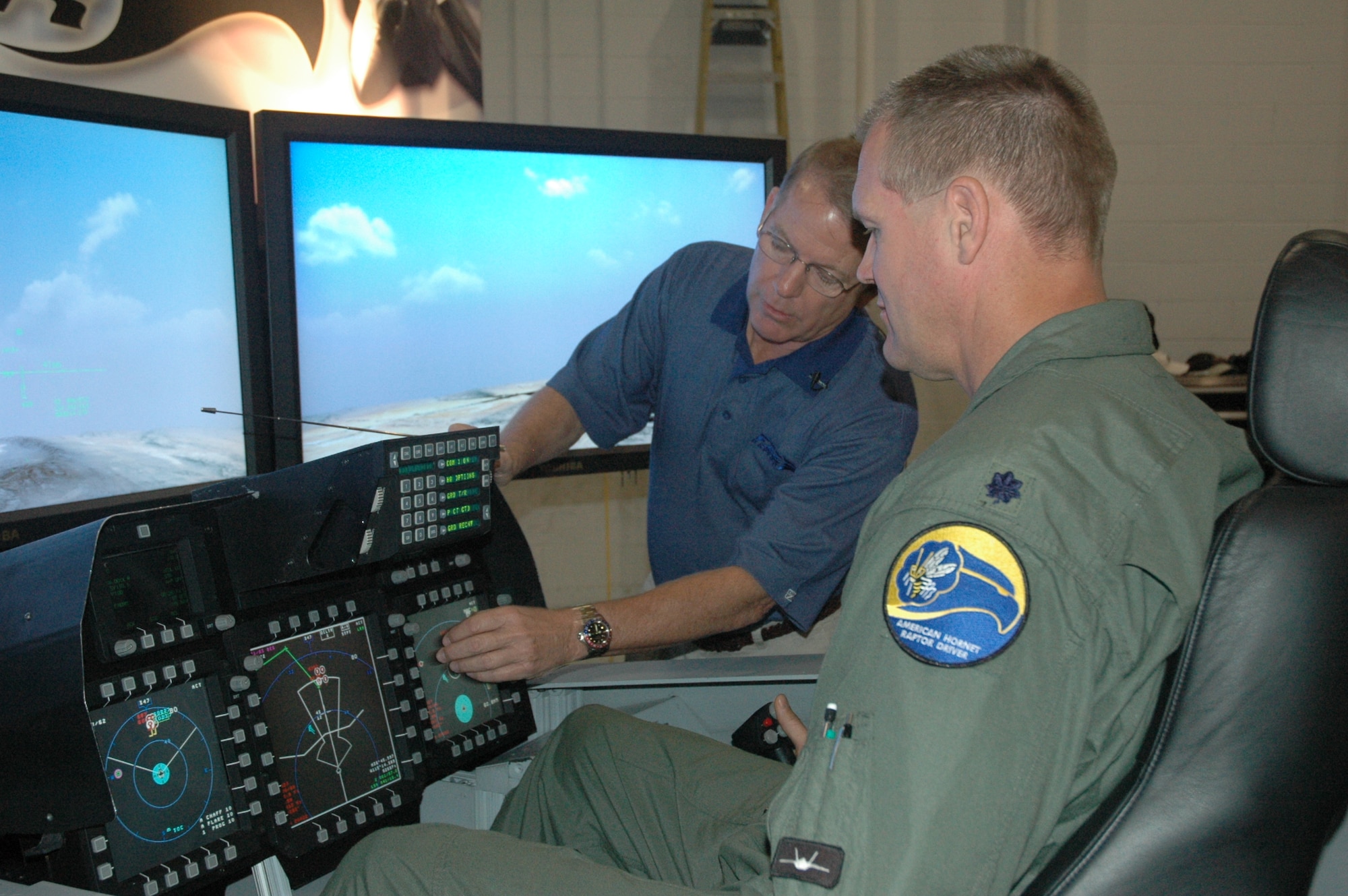 Lt. Col. Tom Kafka, 43rd Fighter Squadron assistant director of operations, demonstrates some of the F-22’s capabilities to local media in a declassified simulator set up by Lockheed Martin in preparation for a red carpet tour here today. The tour was in celebration of the first F-22 basic-course graduation. The graduation ceremony will be held at the Heritage Club Nov. 1. (U.S. Air Force photo/Staff Sgt. Vesta M. Anderson)