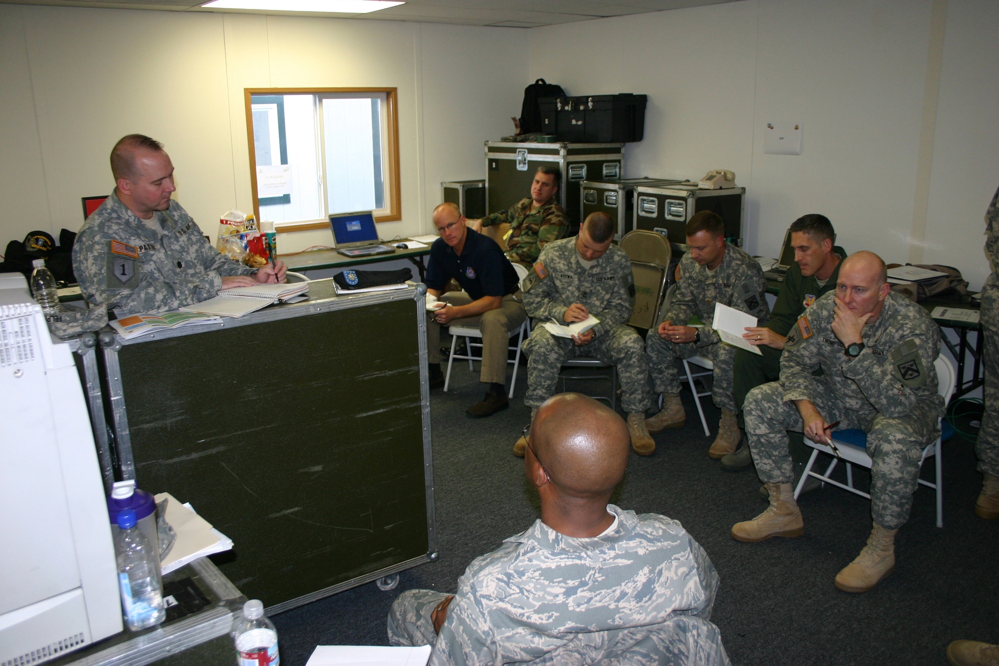 JWFC, JFIIT, and BCTP team members discuss observations at a daily hot wash during the UE 09-01 MRX in Ft. Lewis, Wash. (JFIIT photo/Casey Bain)