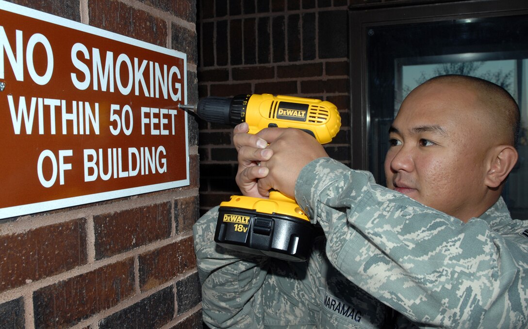 Staff Sgt. Andrew Maramag, 28th Civil Engineer Squadron unaccompanied housing manager, attaches a sign to the outside wall of a dorm here, Oct. 31. The dorm managers are applying these signs to ensure Airmen living in the dorms are informed of the base policy on smoking around the dorms and cannot site they do not when reprimanded. (U.S. Air Force photo/Airman 1st Class Joshua J. Seybert)