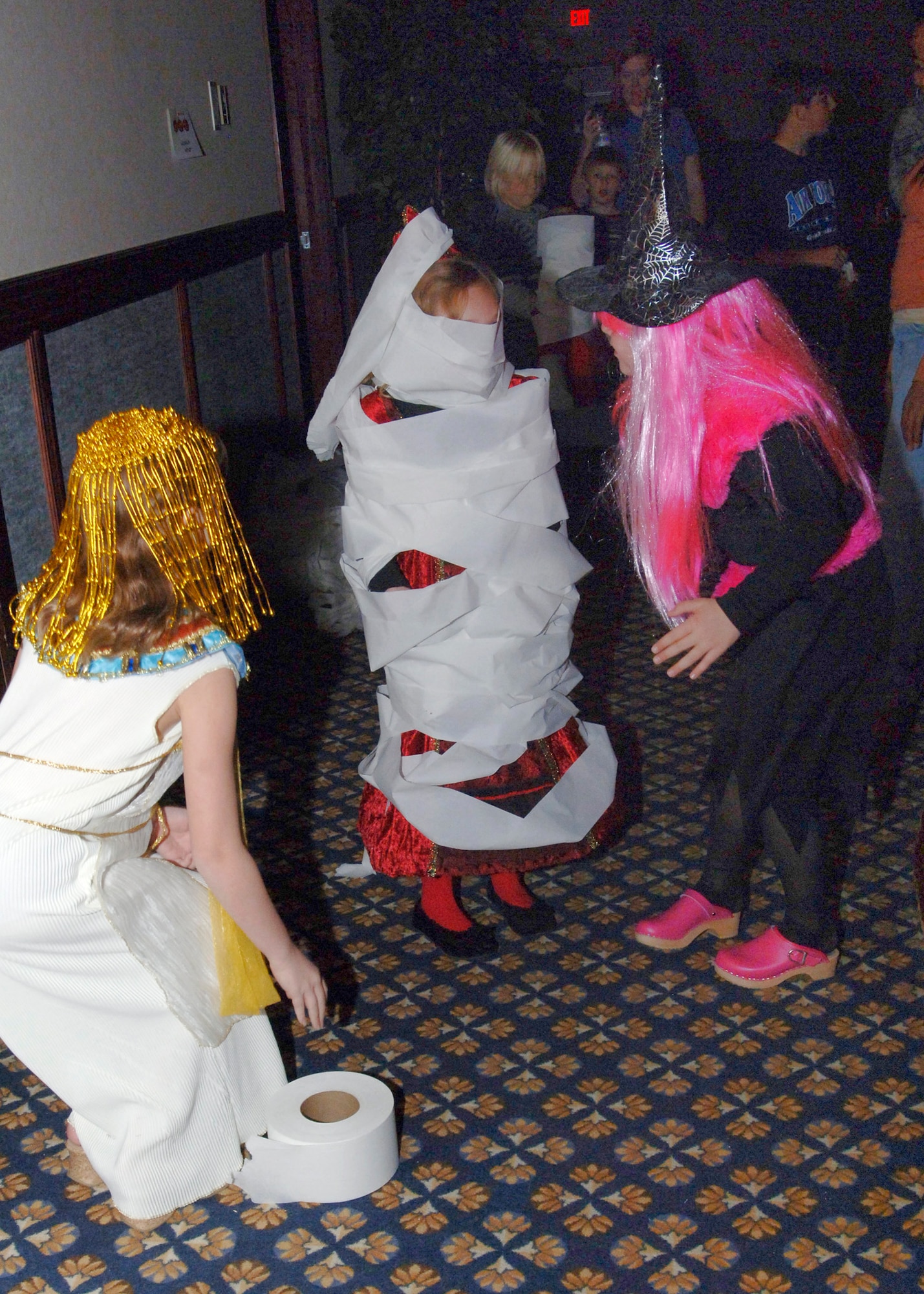 FAIRCHILD AIR FORCE BASE, Wash. – Two children dressed up as an Egyptian pharaoh and a witch, play “Mummy Wrap” by twirling a friend in rolls of toilet paper while at the FAN Club Boo Bash Oct. 29. (U.S. Air Force photo / Airman 1st Class Melissa L. Barnett)