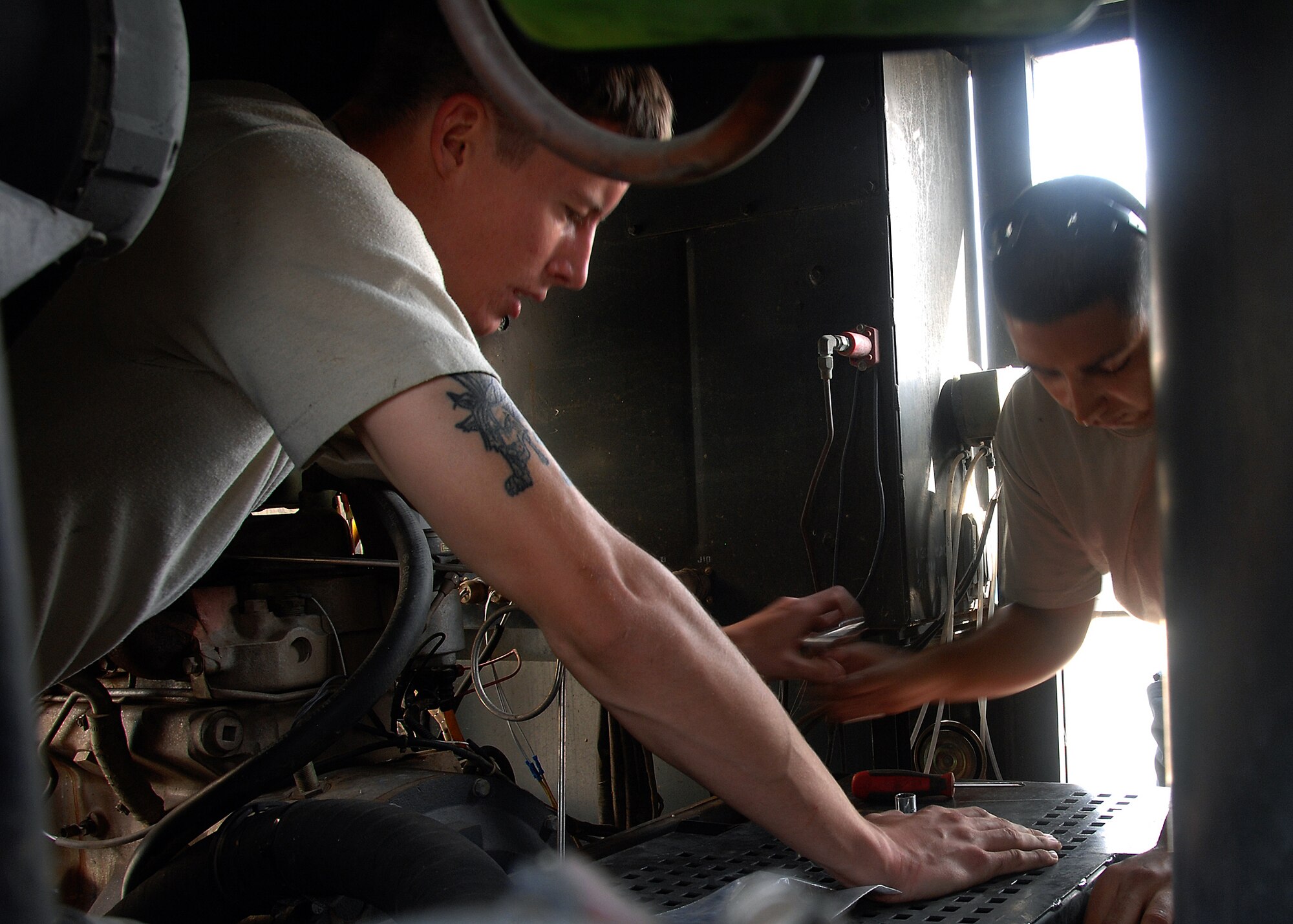 SOUTHWEST ASIA -- Staff Sgt. Jason Castillo, right, hands Senior Airman Carl Frame a socket wrench as they repair an MA-3D portable air conditioning system on Oct. 28 at an air base in Southwest Asia. Both Airmen are deployed to the 386th Expeditionary Maintenance Squadron Aerospace Ground Equipment flight. The AGE flight provides direct ground support for C-130 aircraft, C-17 aircraft and various transient airframes. They also perform scheduled inspections and countless unscheduled maintenance actions on their fleet of more than 200 powered and non-powered pieces of equipment. (U.S. Air Force photo/Tech. Sgt. Raheem Moore)