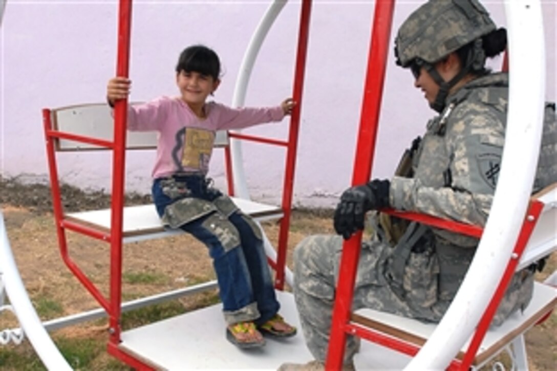 U.S. Army 1st Lt. Rosita Rodriguez and Worda, age 6, a neighborhood little girl try out a new swing at the grand opening of Dover Park in the Qahira neighborhood in the Adhamiyah District of Baghdad, Iraq, Oct. 28, 2008. Rodriguez is a civil affairs team chief, Company C, 404th Civil Affairs Battalion, attached to 3rd Brigade Combat Team, 4th Infantry Division, Multi-National Division-Baghdad. The park, refurbished by a Multi-National Division-Baghdad contract and is the first public park in the