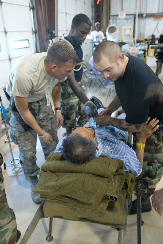 Air Force Technical Sergeant Martelle (right), Senior Airman William Stephan (left) and Senior Airman Curtis Simmons (back) from the 136th Airlift Wing, Texas Air National Guard secures a special needs person awaiting to airlift to safety at the SE Texas Regional Airport, Beaumont , Texas, in support of Hurricane Gustav Relief efforts, 30 August 2008. (Photo by TSgt Charles Hatton) 