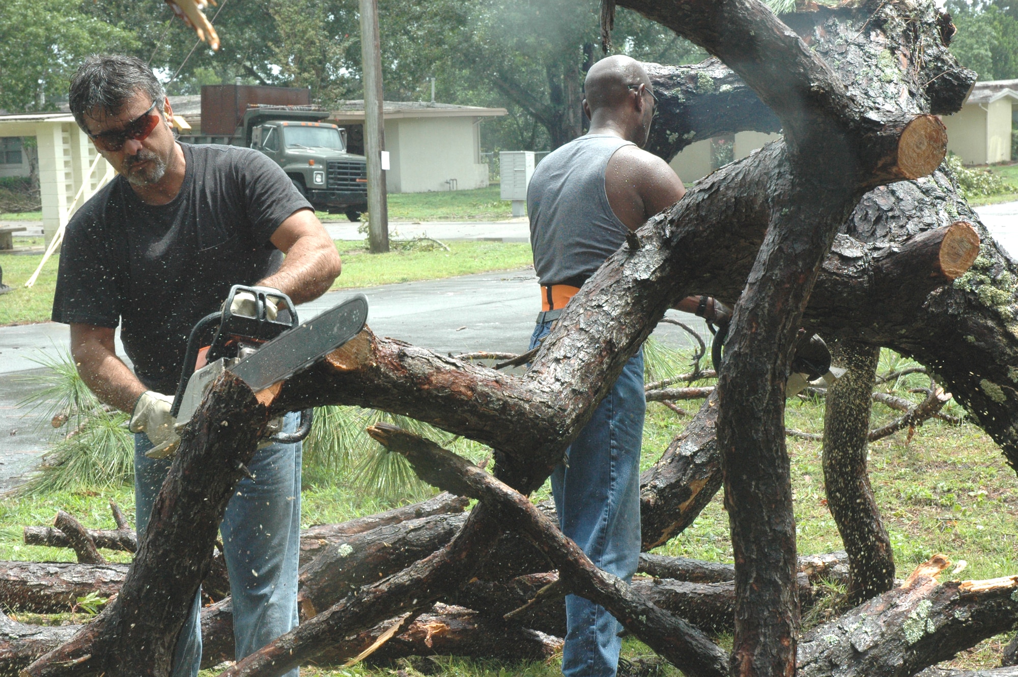 Mike Esquiveo (left) and Russell Kelly, 796th Civil Engineer Squadron, cut away limbs from a tree that landed on the home of Airman 1st Class Devin Hennessy, 46th Operations Support Squadron, Sept. 1 after a tornado touched down in Eglin's housing area. (U.S. Air Force photo by Tech. Sgt. Brian Jones)