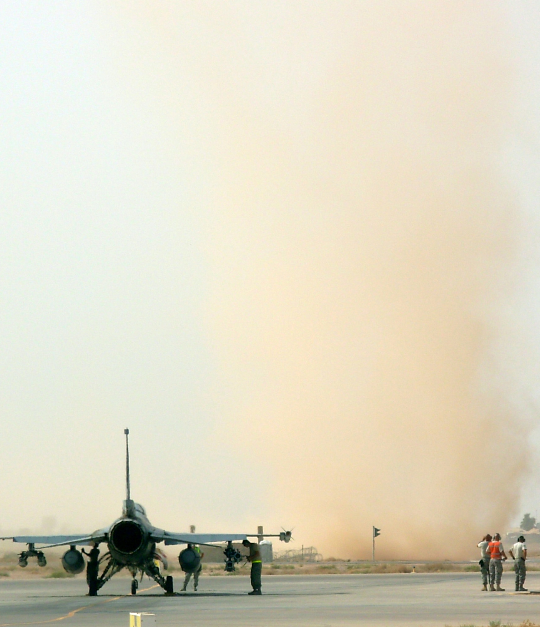 JOINT BASE BALAD, Iraq -- A dust devil blows through the airfield near an F-16 Fighting Falcon here Aug. 28. The aircraft was in the north de-arm area after returning from a mission. The flat terrain, clear skies and light wind typical of summers here makes dust devils a common phenomenon. While they can reach more than 1,000 meters in height, they are much less intense than tornadoes. (U.S. Air Force photo/Capt. Jeffrey Godzik)