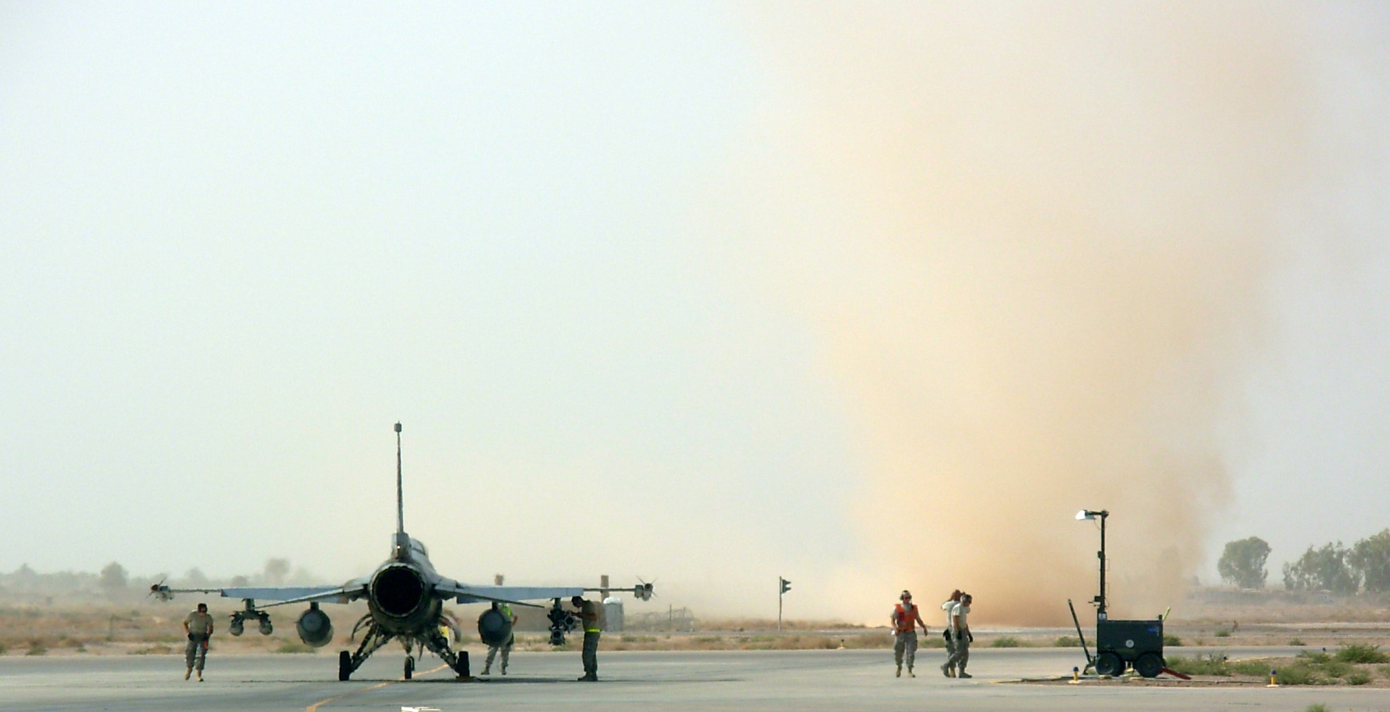 JOINT BASE BALAD, Iraq -- A dust devil blows through the airfield near an F-16 Fighting Falcon here Aug. 28. The aircraft was in the north de-arm area after returning from a mission. The flat terrain, clear skies and light wind typical of summers here makes dust devils a common phenomenon. While they can reach more than 1,000 meters in height, they are much less intense than tornadoes. (U.S. Air Force photo/Capt. Jeffrey Godzik)